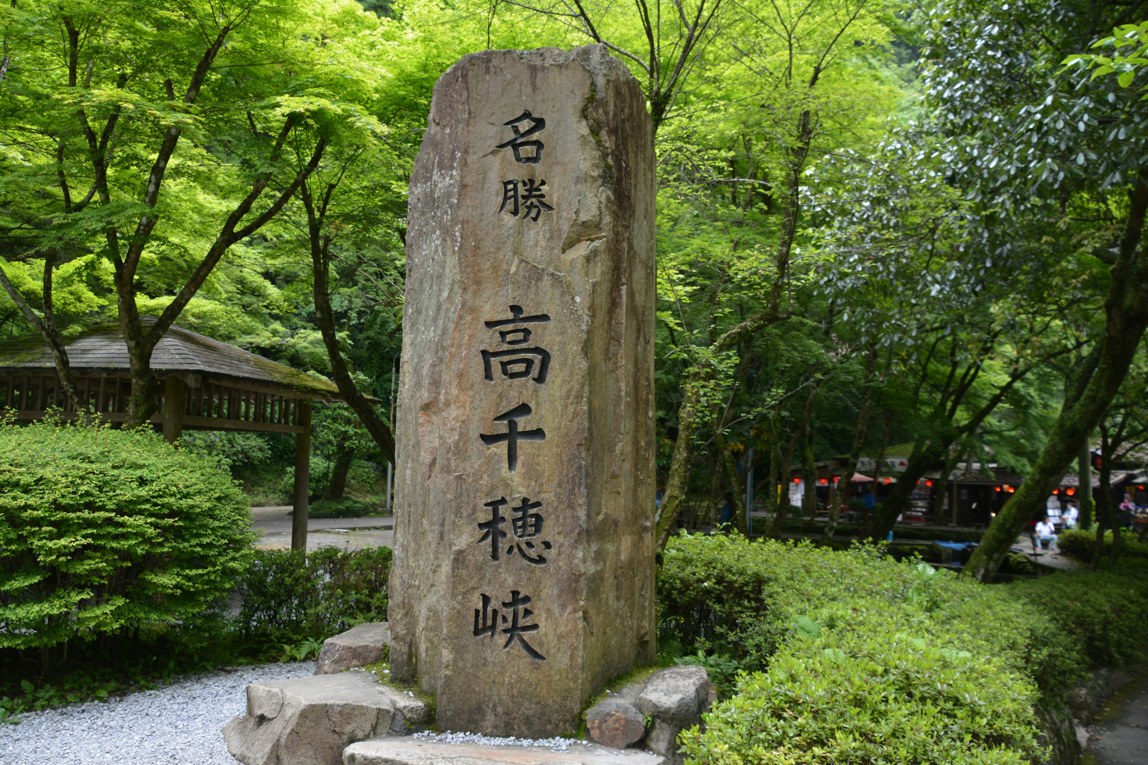 A stone monument of Takachiho Gorge surrounded by green trees