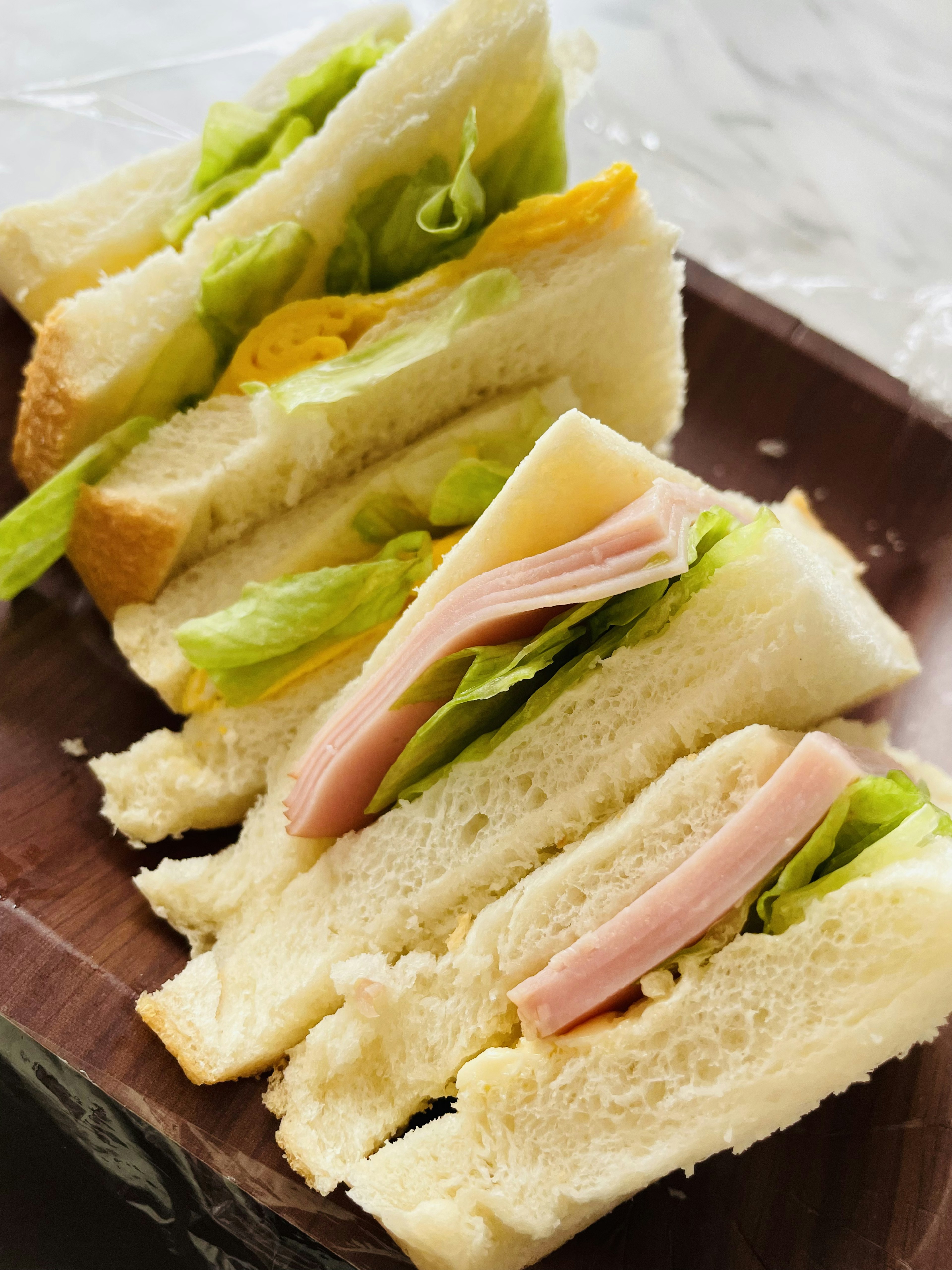 Un plato de sándwiches en rodajas con relleno de huevo, lechuga y jamón