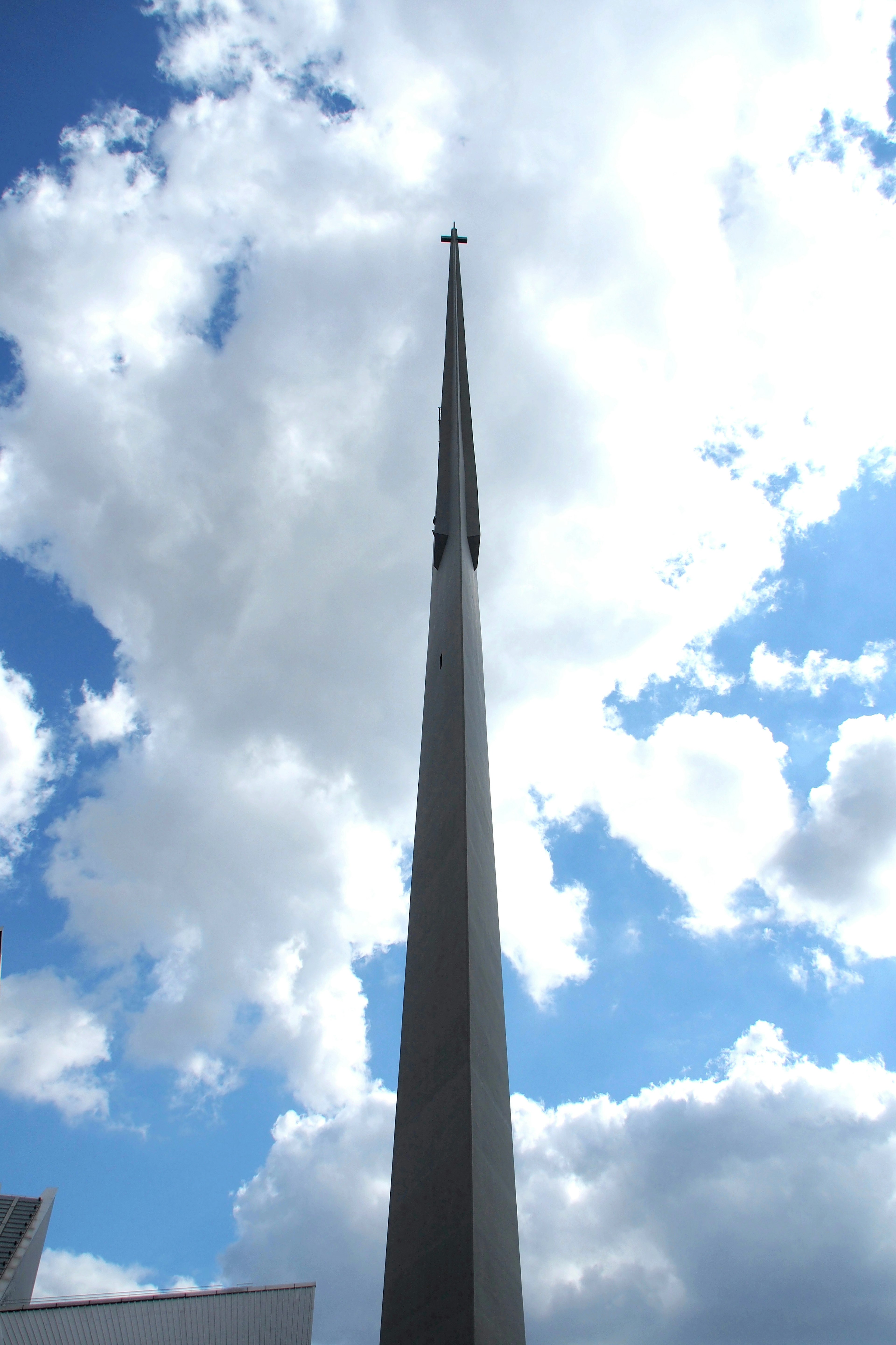 Flèche d'église haute contre un ciel bleu et des nuages blancs