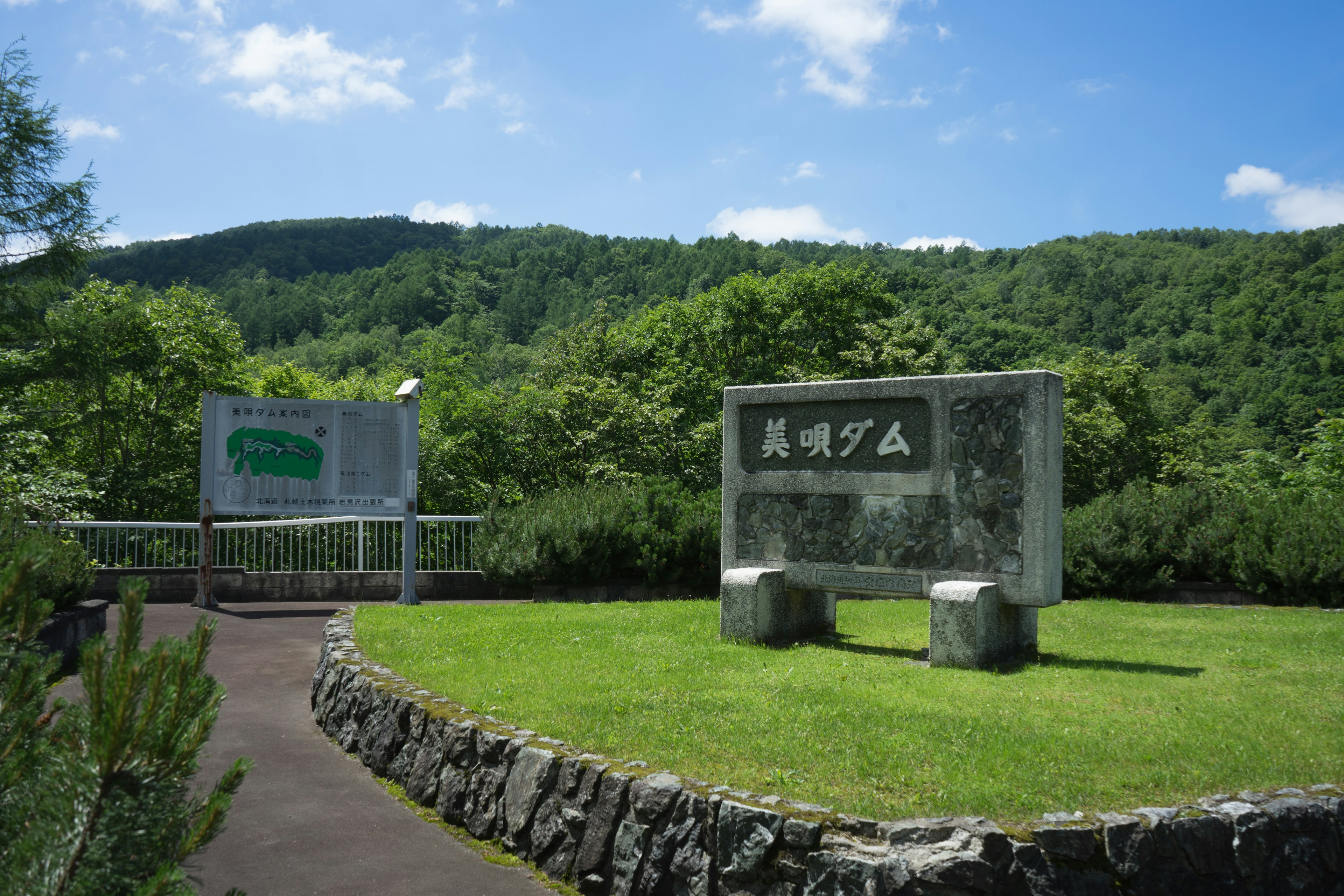 Entrée de parc avec des monuments en pierre et des montagnes verdoyantes en arrière-plan