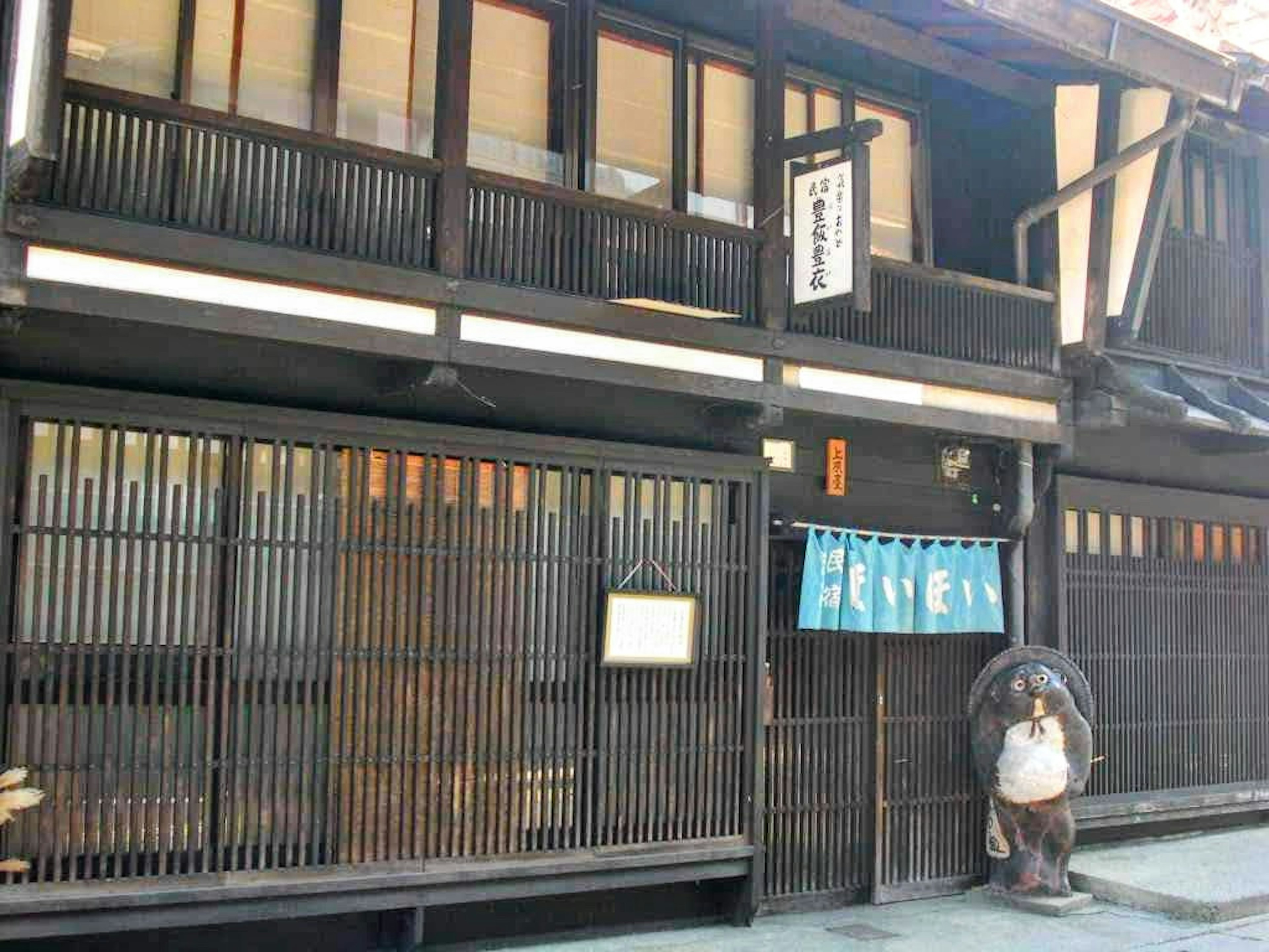 Exterior de una casa de pueblo japonés tradicional estructura de madera negra ventanas de listones verticales cortina azul