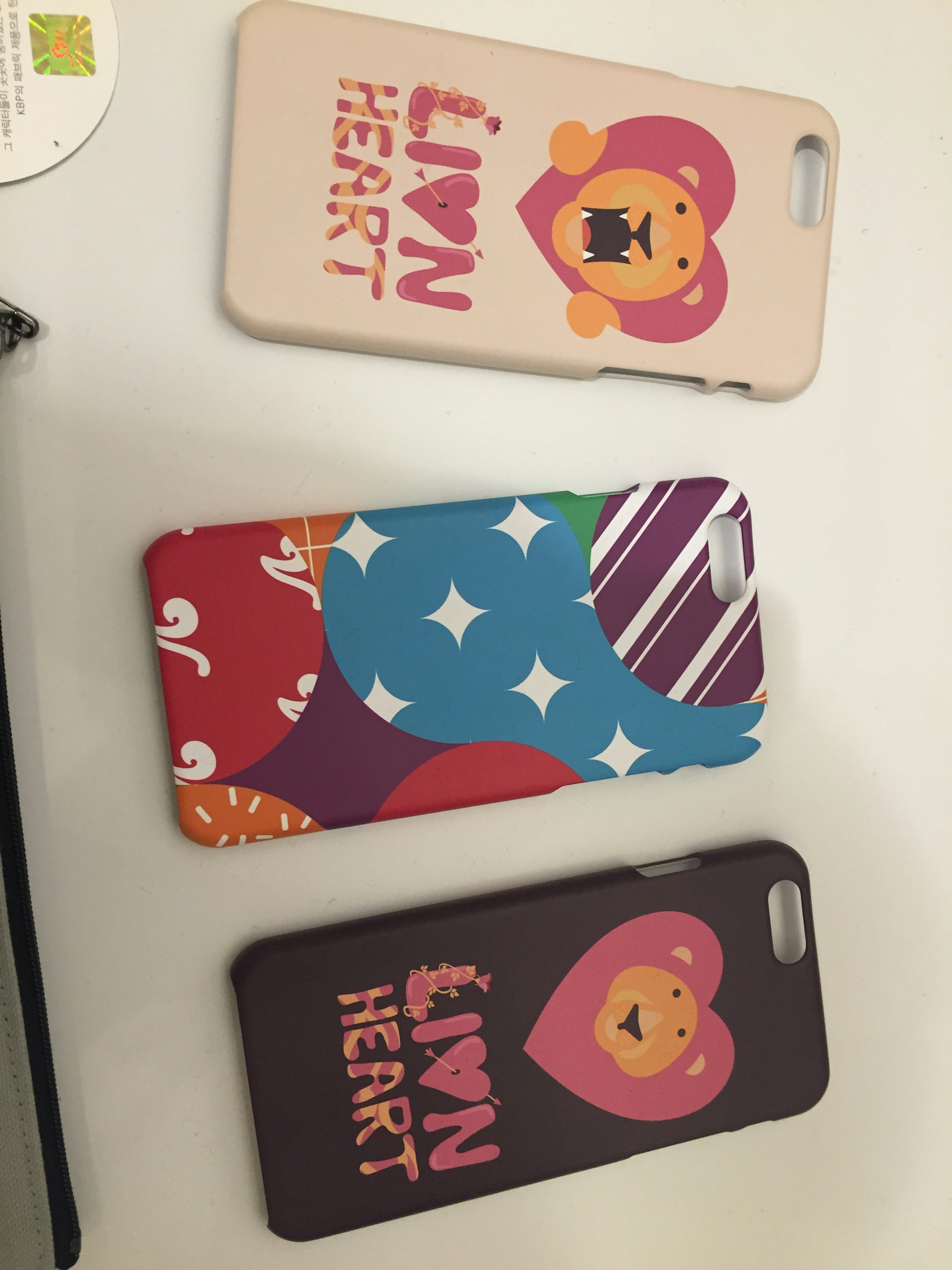 Three colorful smartphone cases featuring a lion illustration and the words LION HEART