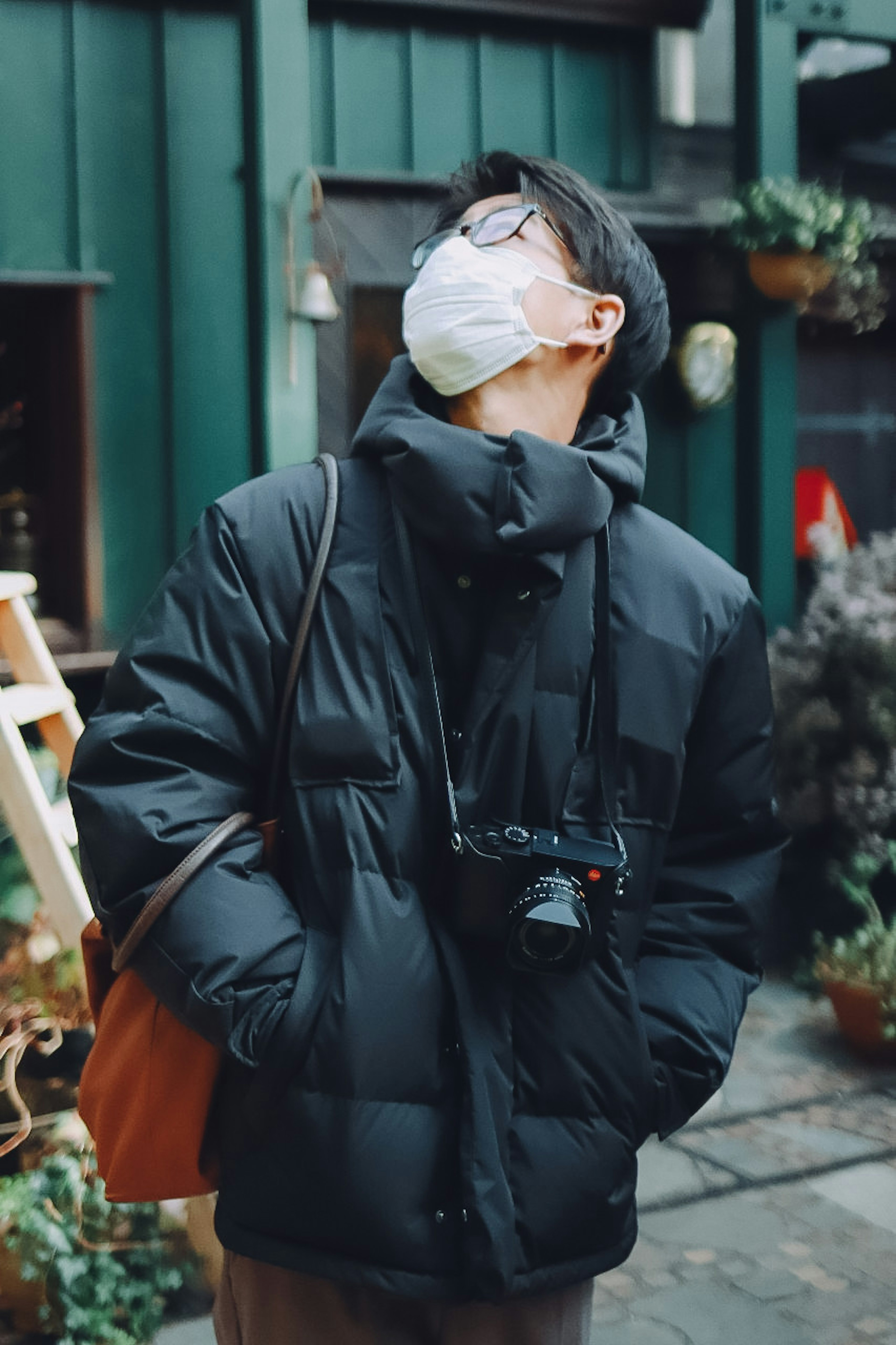 A man wearing a mask looking up while holding a camera