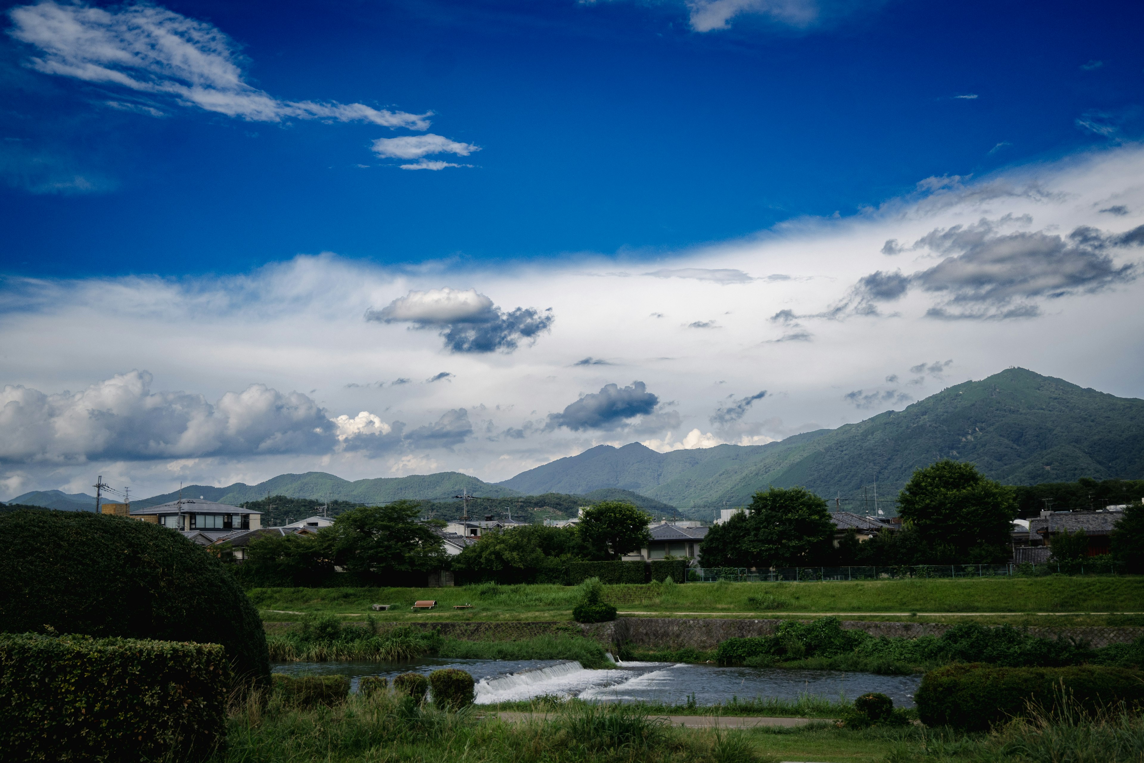 Vista panoramica con cielo blu brillante nuvole campi verdi e montagne sullo sfondo