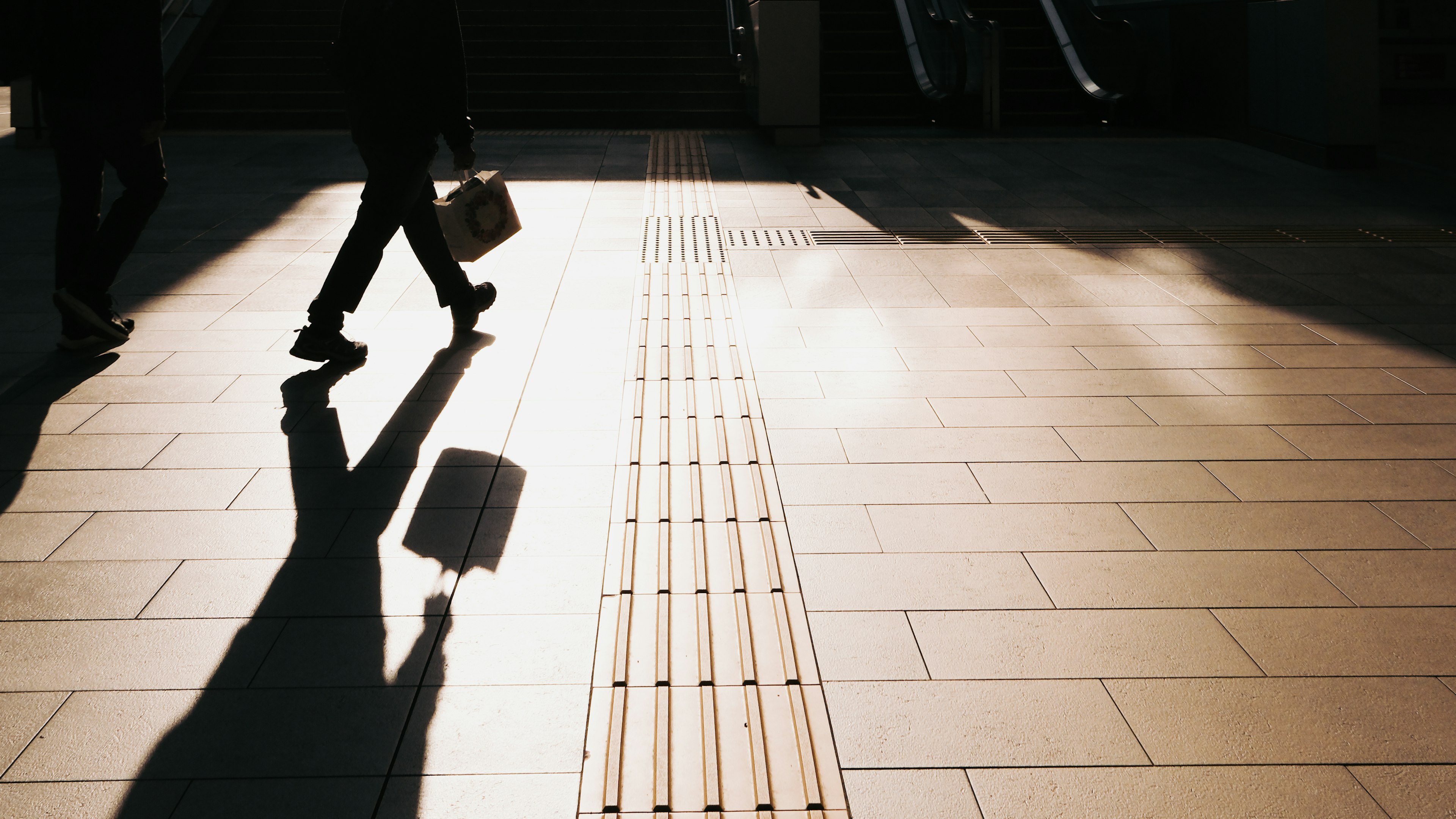 Silhouette d'un homme d'affaires marchant avec une valise sur un sol carrelé