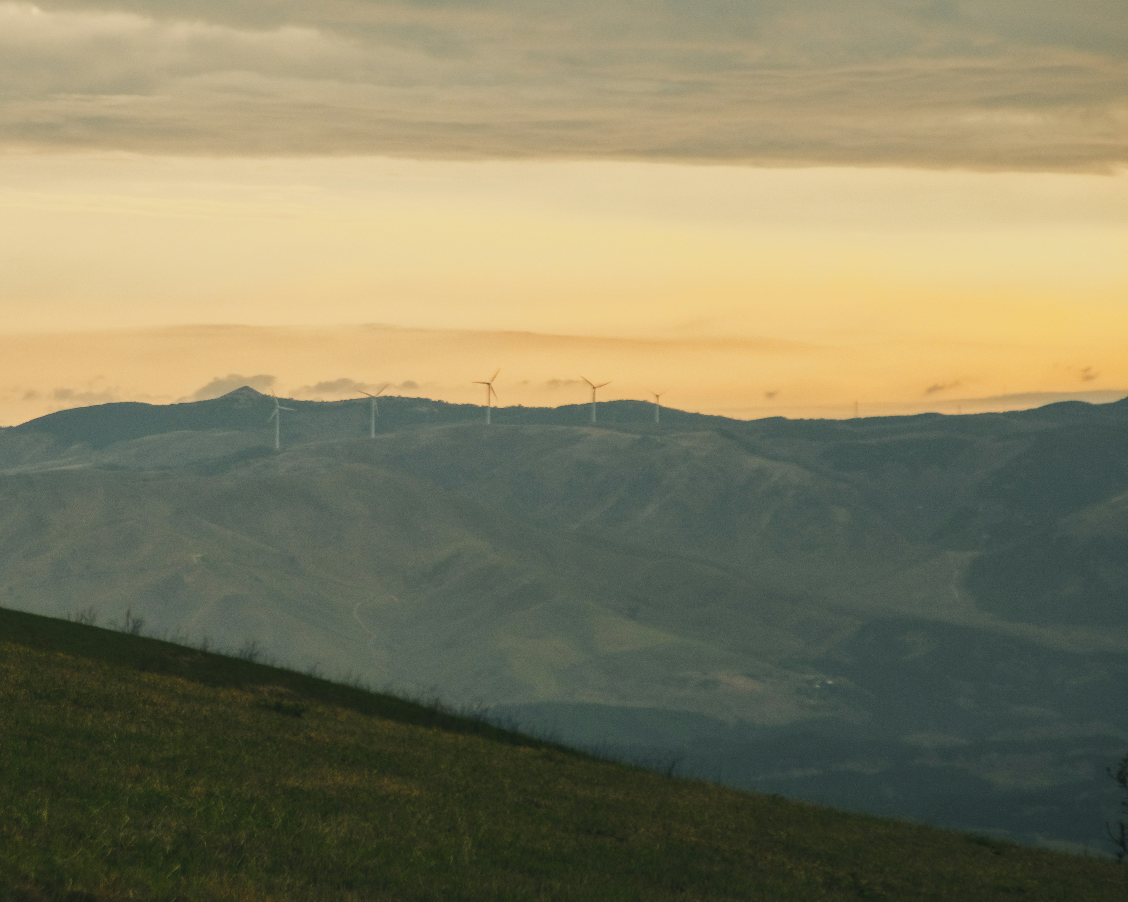 Paysage de montagne avec des éoliennes et un ciel orange