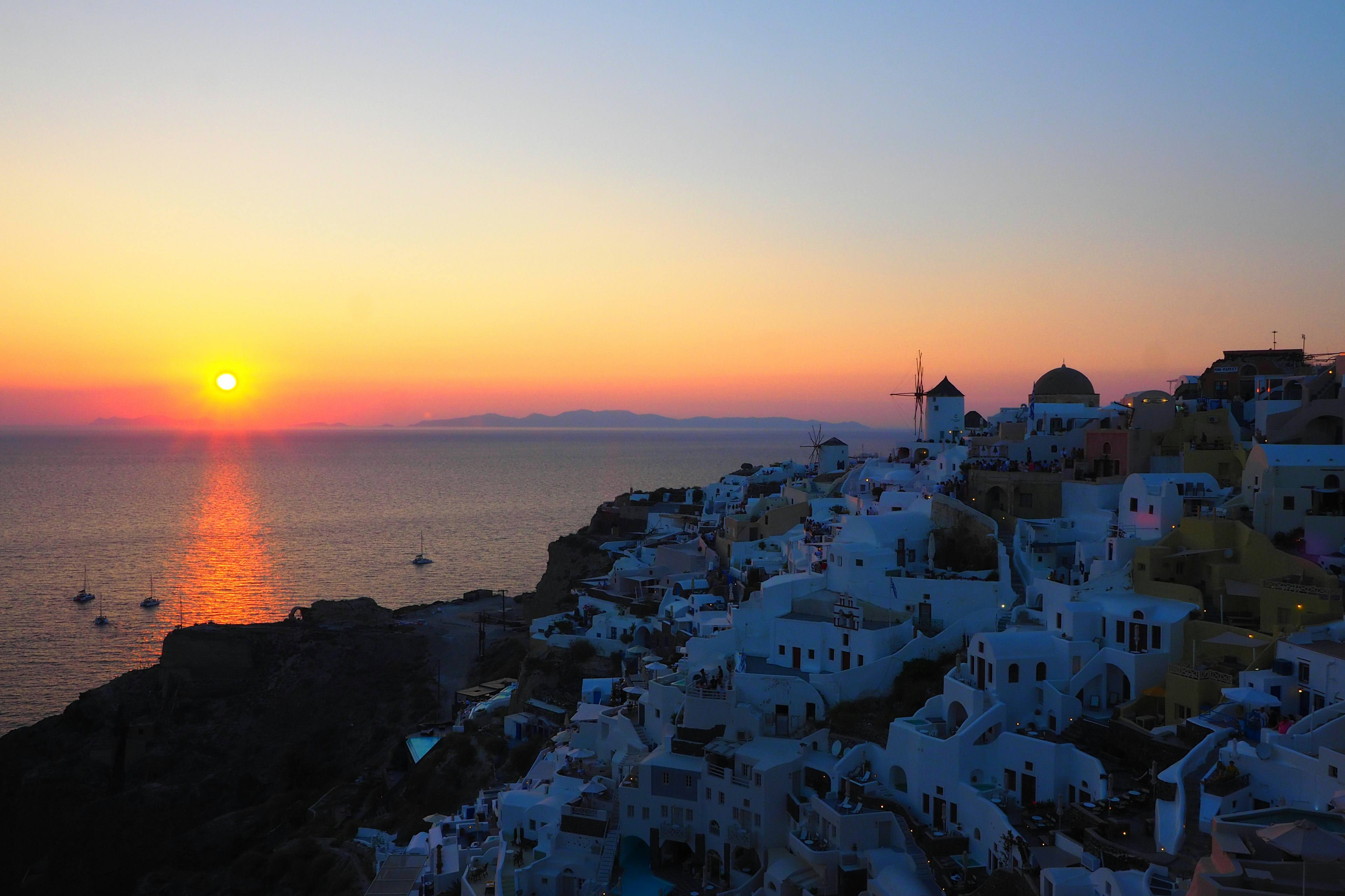 Matahari terbenam yang indah di atas laut di Santorini dengan bangunan putih yang bersiluet