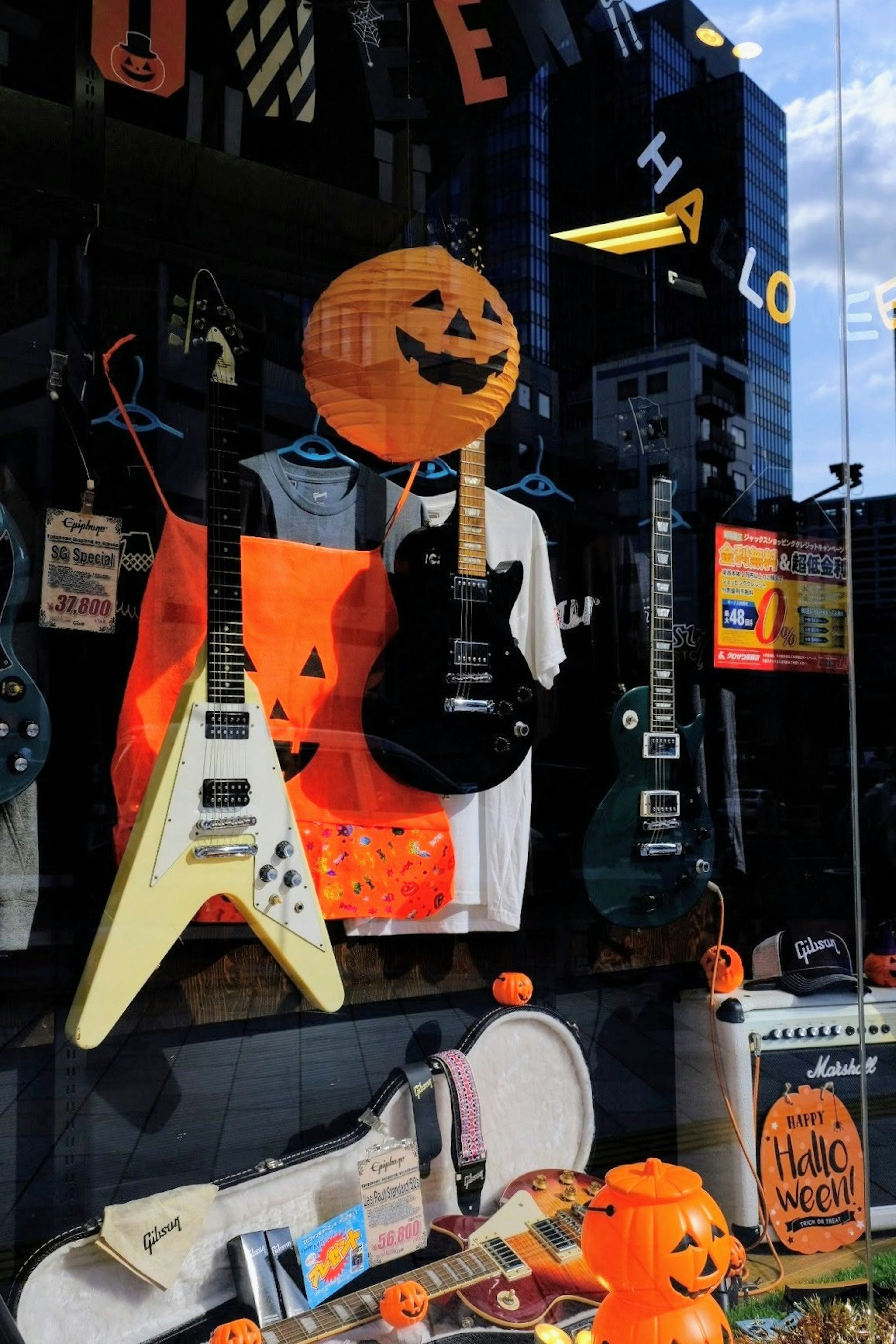 Window display of a music shop decorated for Halloween featuring guitars and orange accents