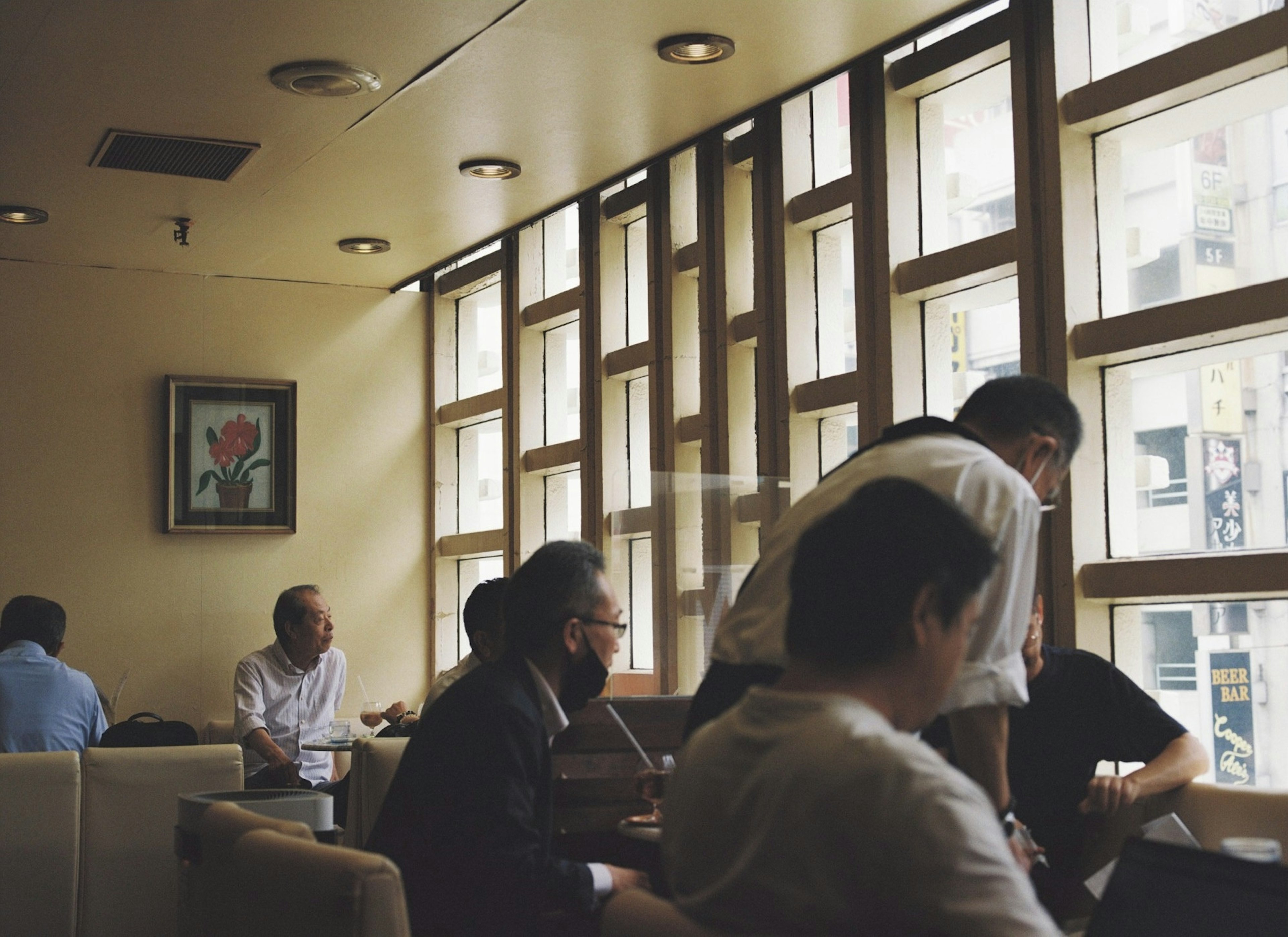 ภายในร้านกาแฟที่มีคนสนทนากันใกล้หน้าต่าง