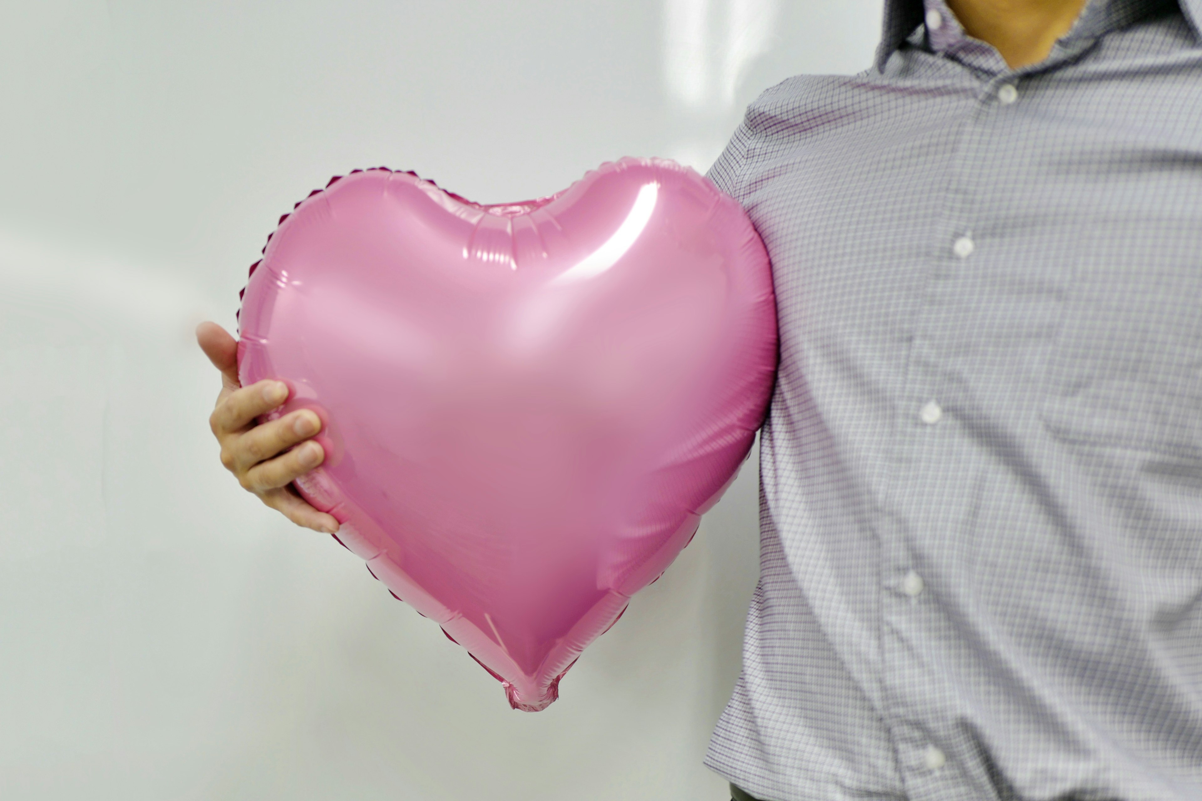 Eine Person, die einen rosa, herzförmigen Ballon hält