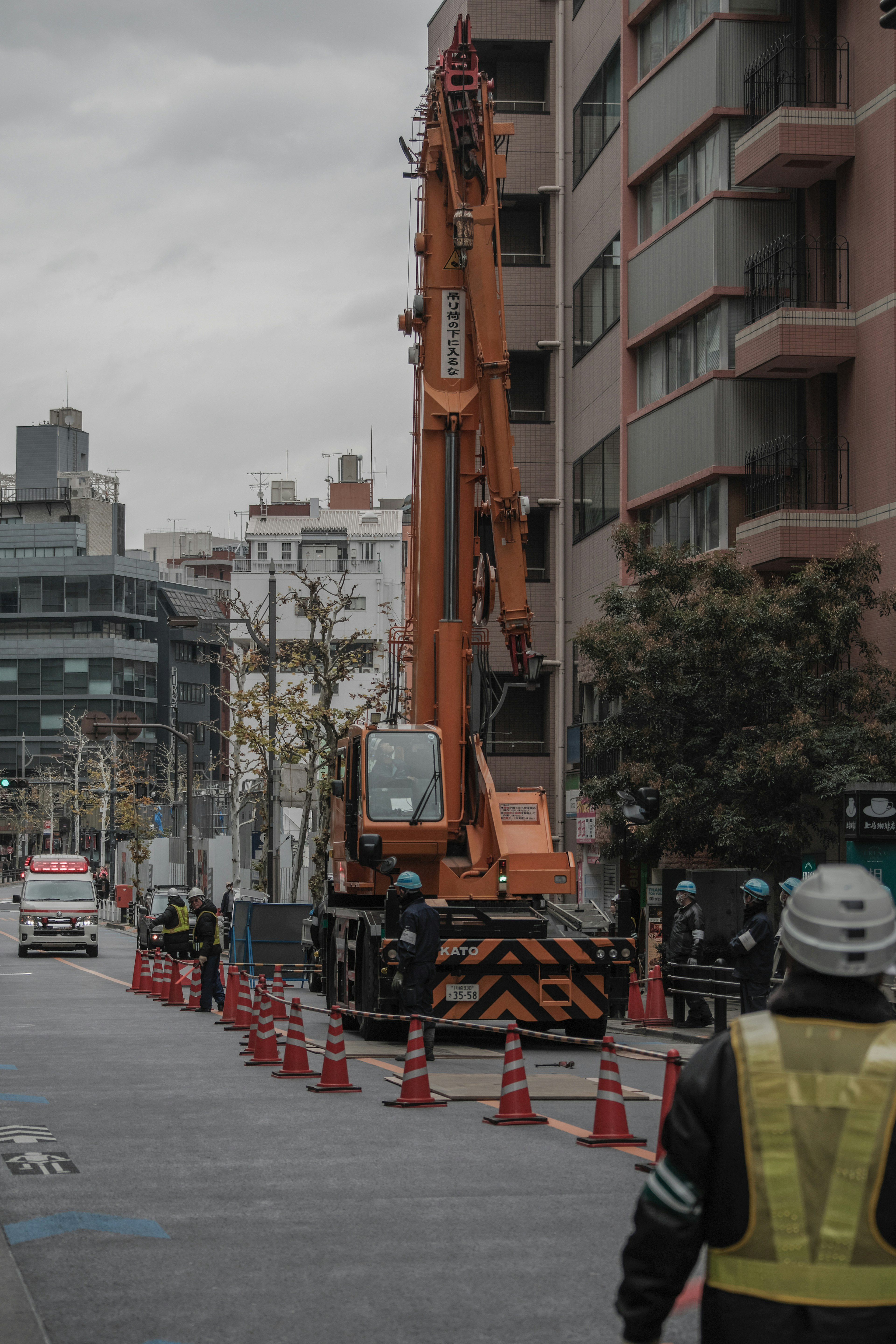 工事現場のオレンジ色のクレーンと作業員がいる風景