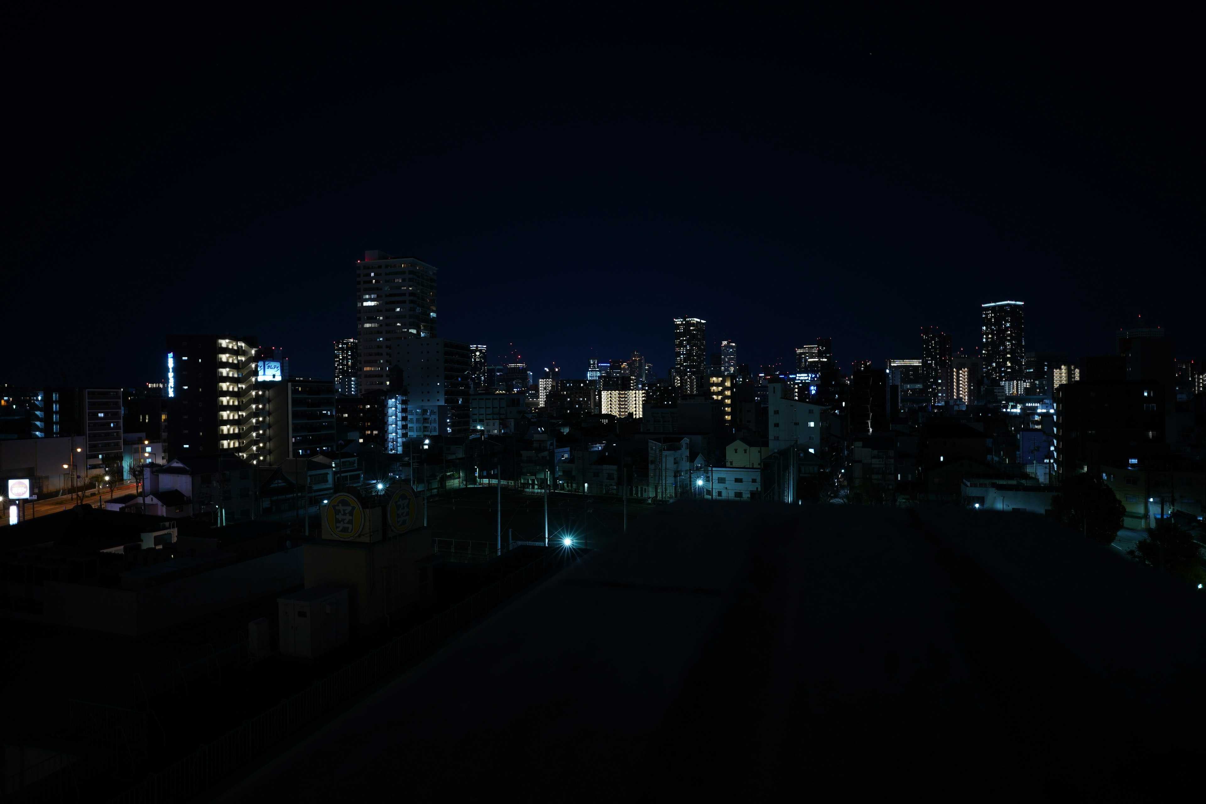 Silhouette de la ville la nuit avec des bâtiments illuminés et un ciel sombre