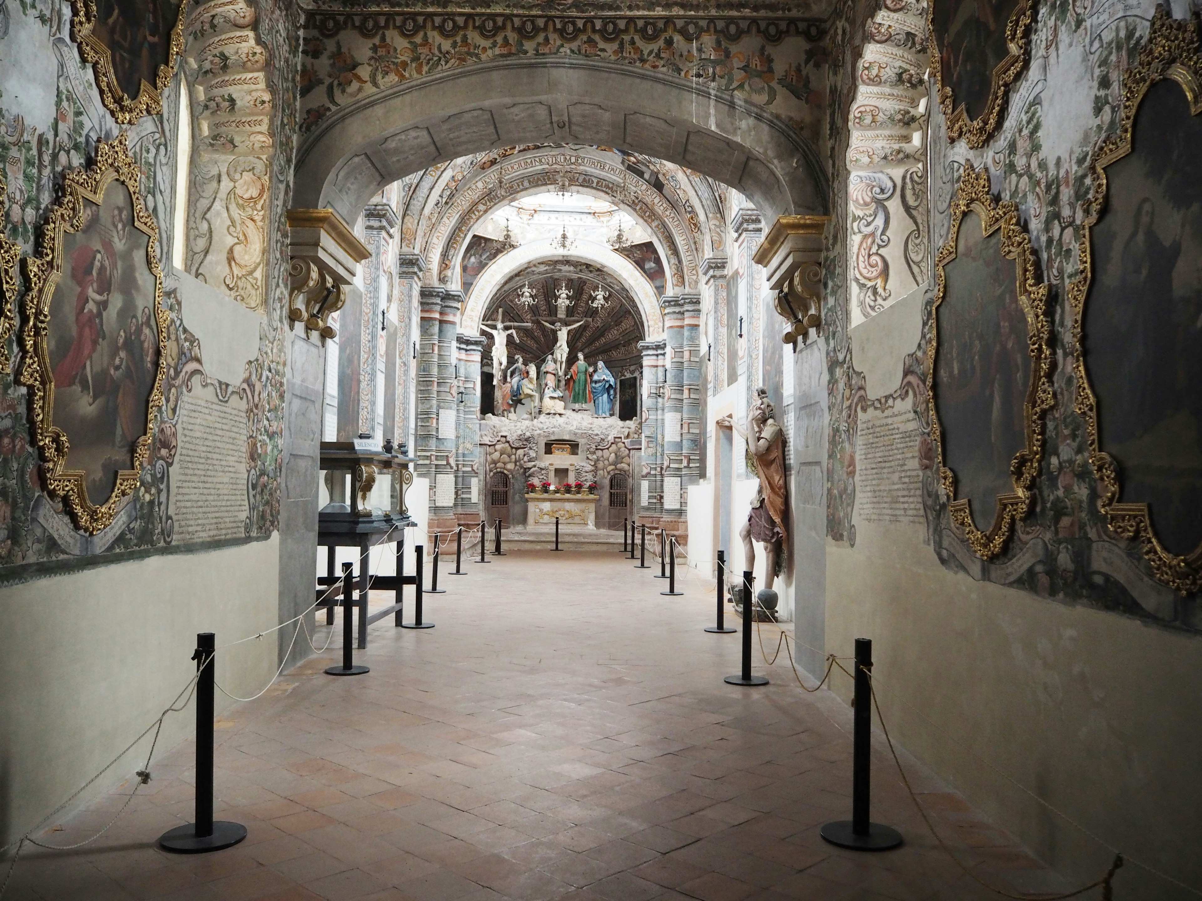 Couloir historique avec de beaux plafonds et des décorations ornées présentant des peintures anciennes sur les murs