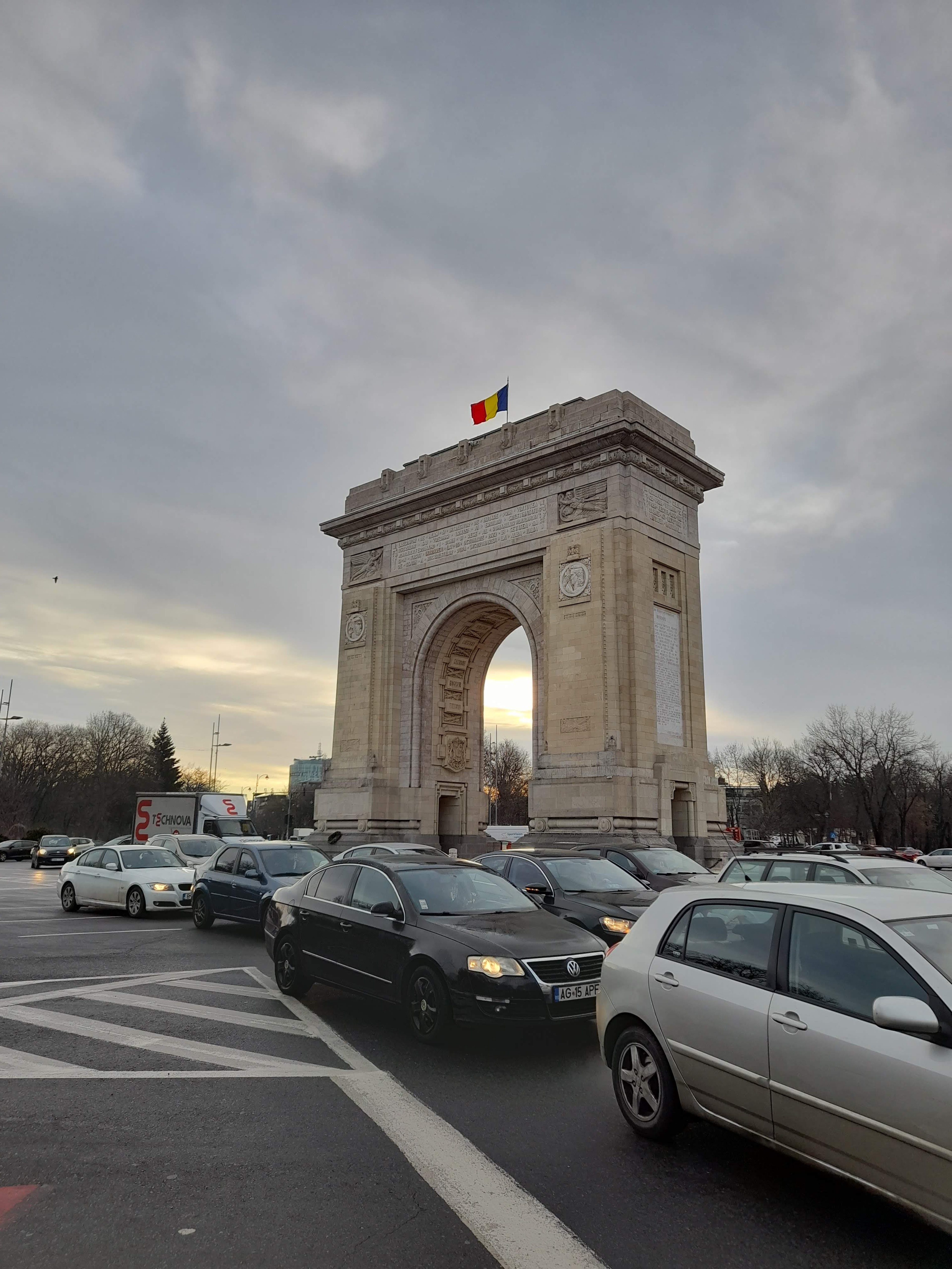 Monumen lengkung Rumania dengan lalu lintas dan langit mendung