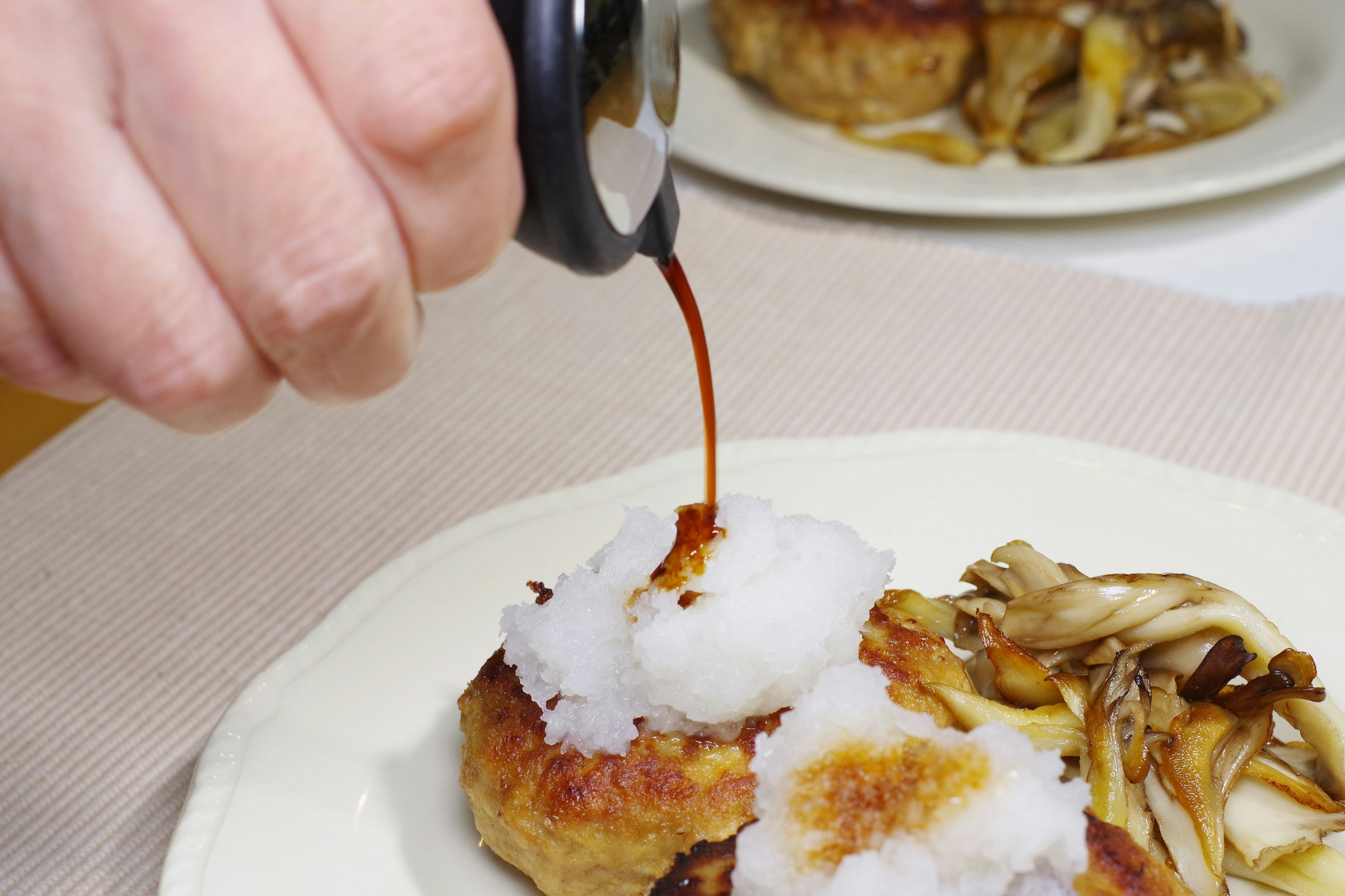 Hand pouring soy sauce over grated daikon on a dish