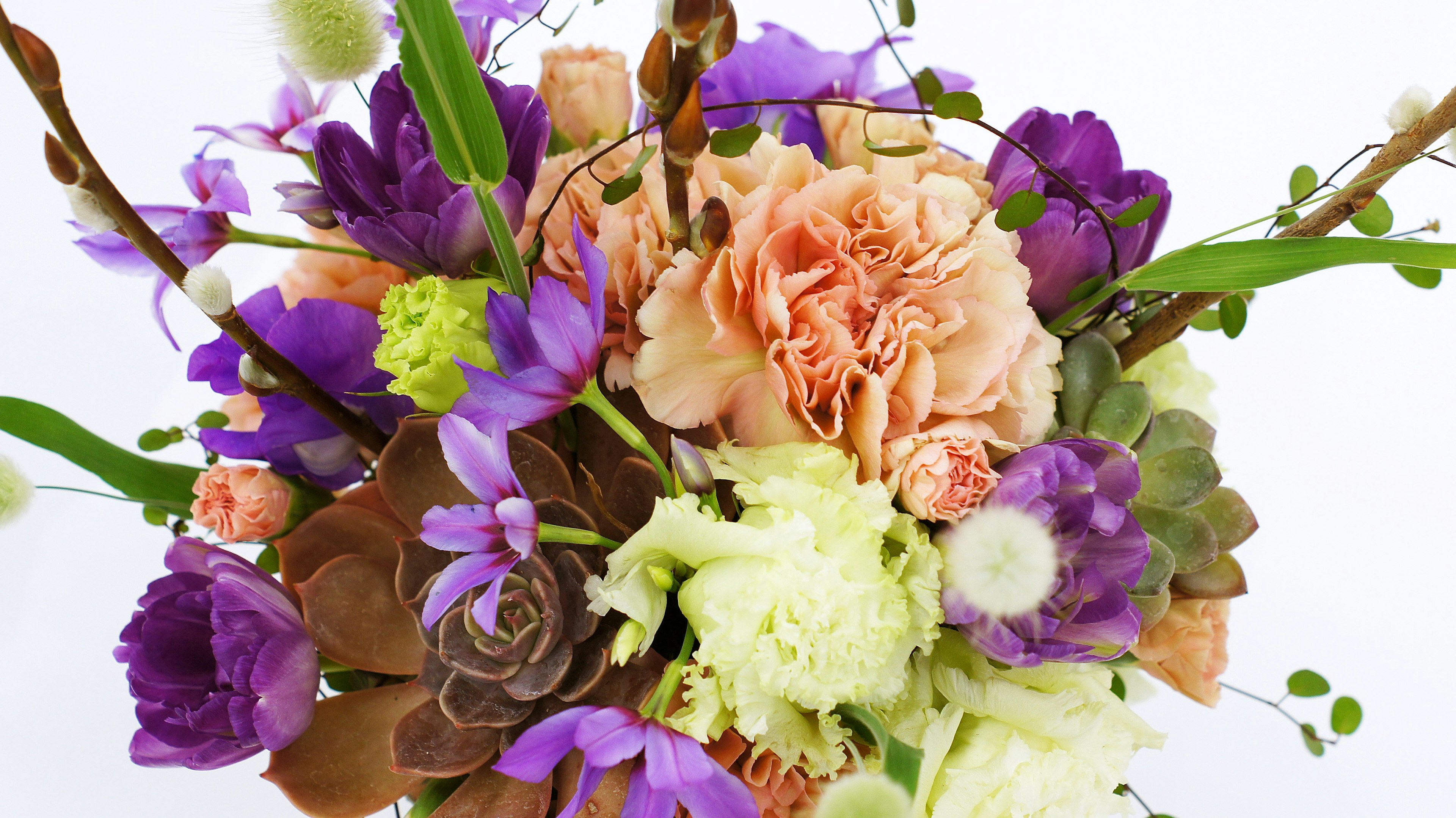 A soft-colored bouquet featuring pink carnations purple flowers and green leaves