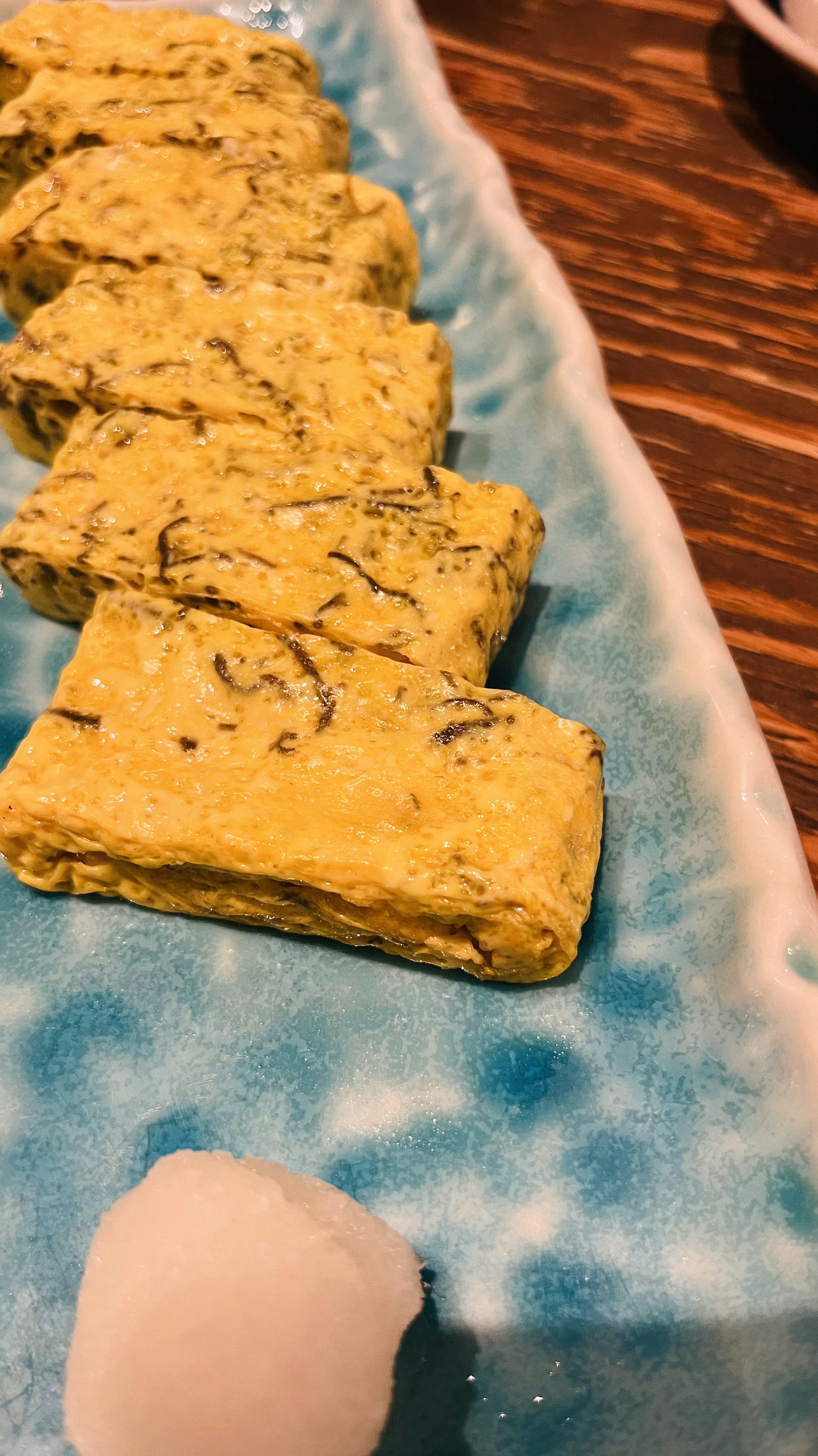 Un hermoso plato azul con rodajas de tortilla japonesa y una porción de rábano daikon rallado blanco