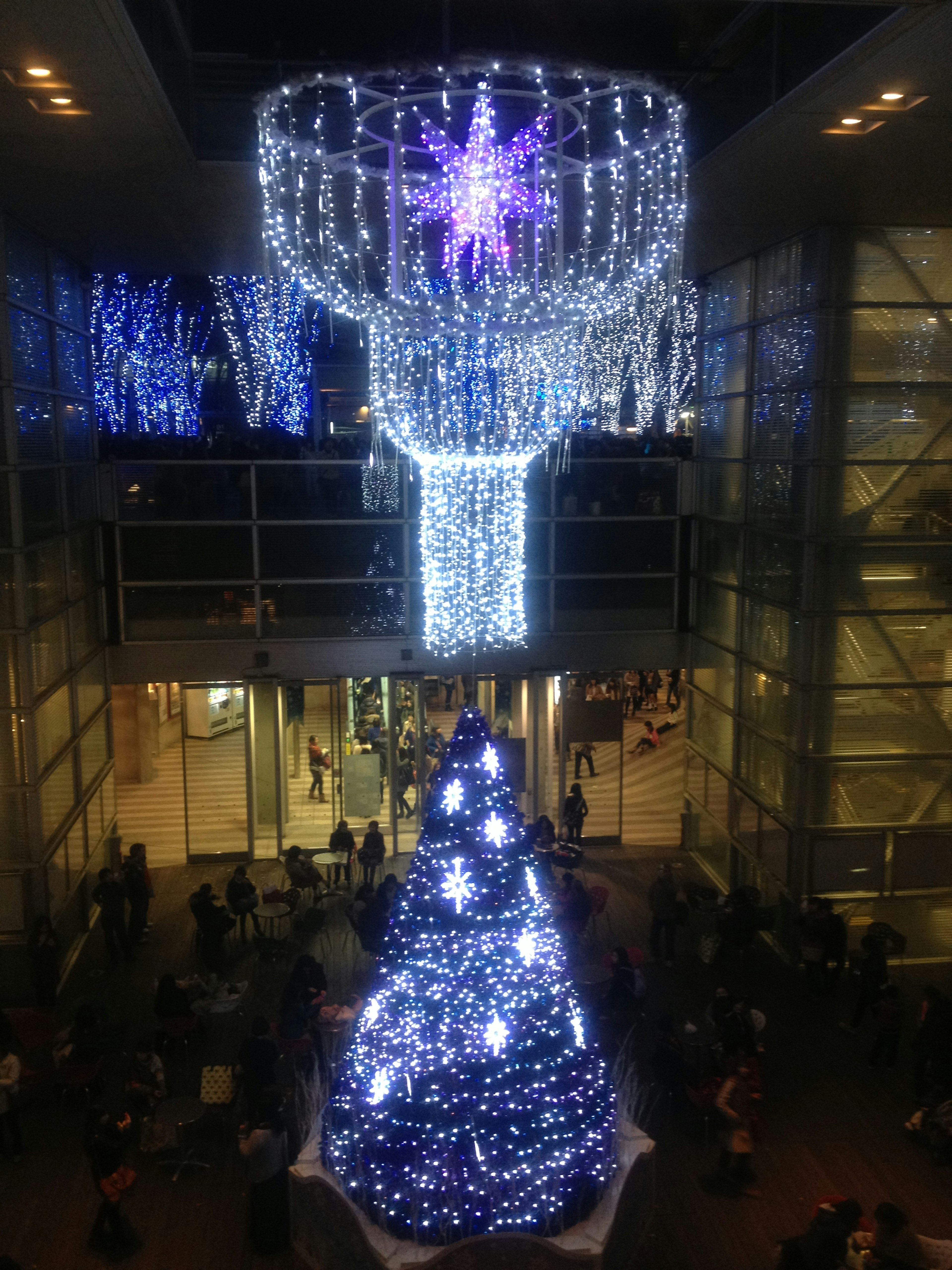 Albero di Natale decorato con luci blu e bianche sotto un lampadario