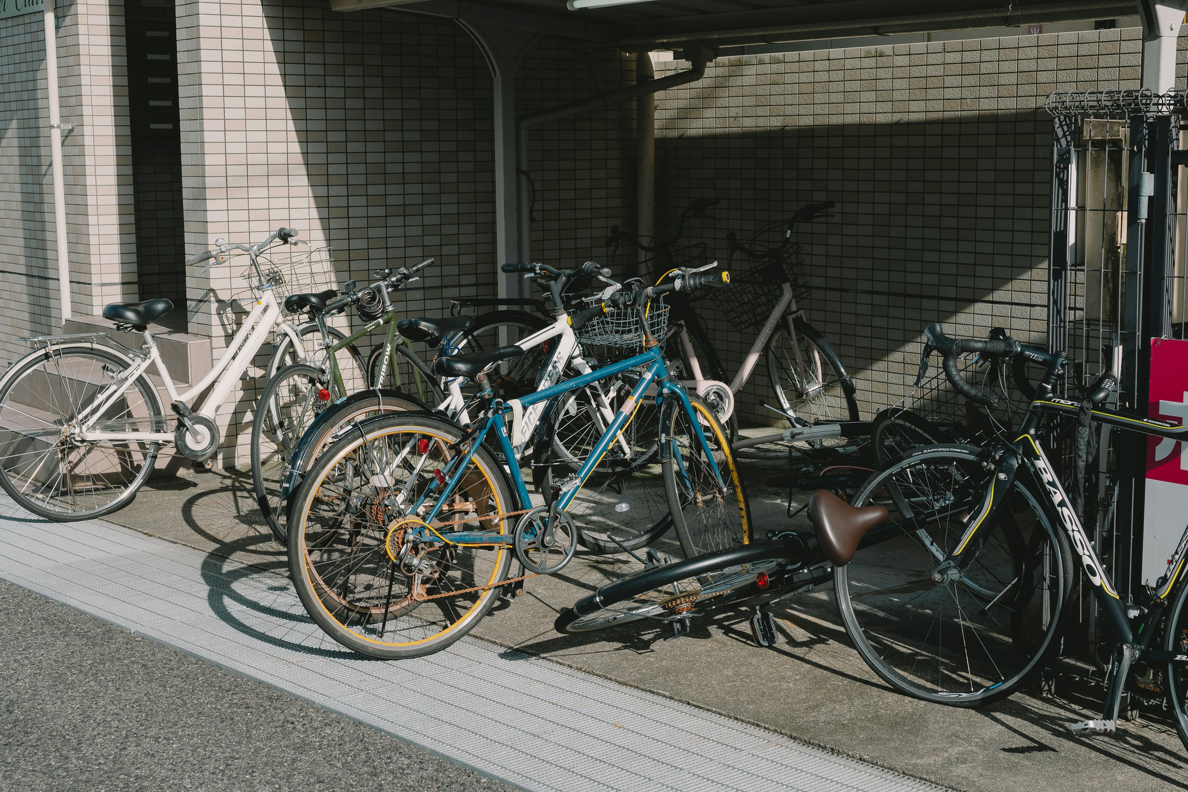 A collection of bicycles parked including white and blue bikes