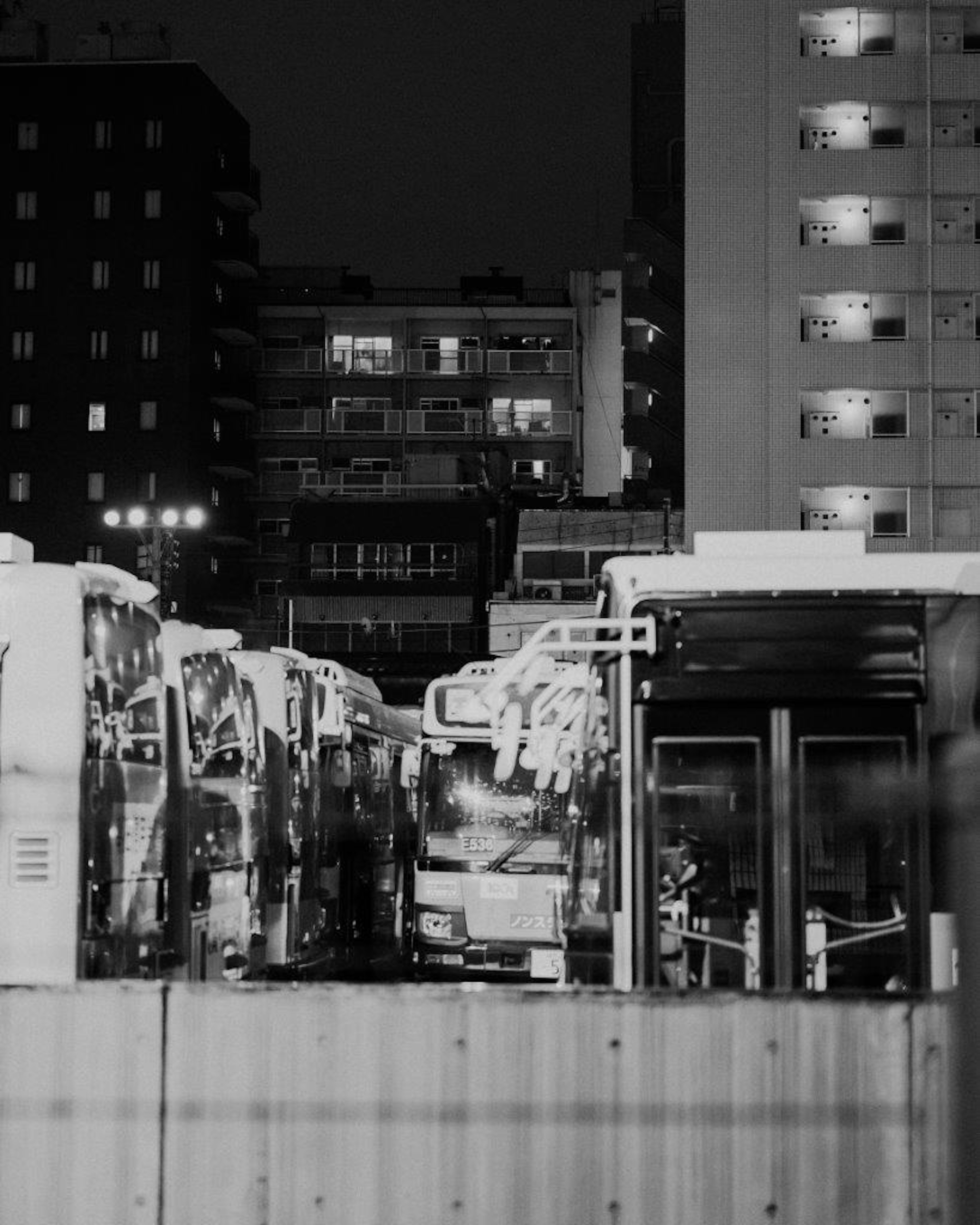 Nighttime city scene featuring parked buses at a bus station