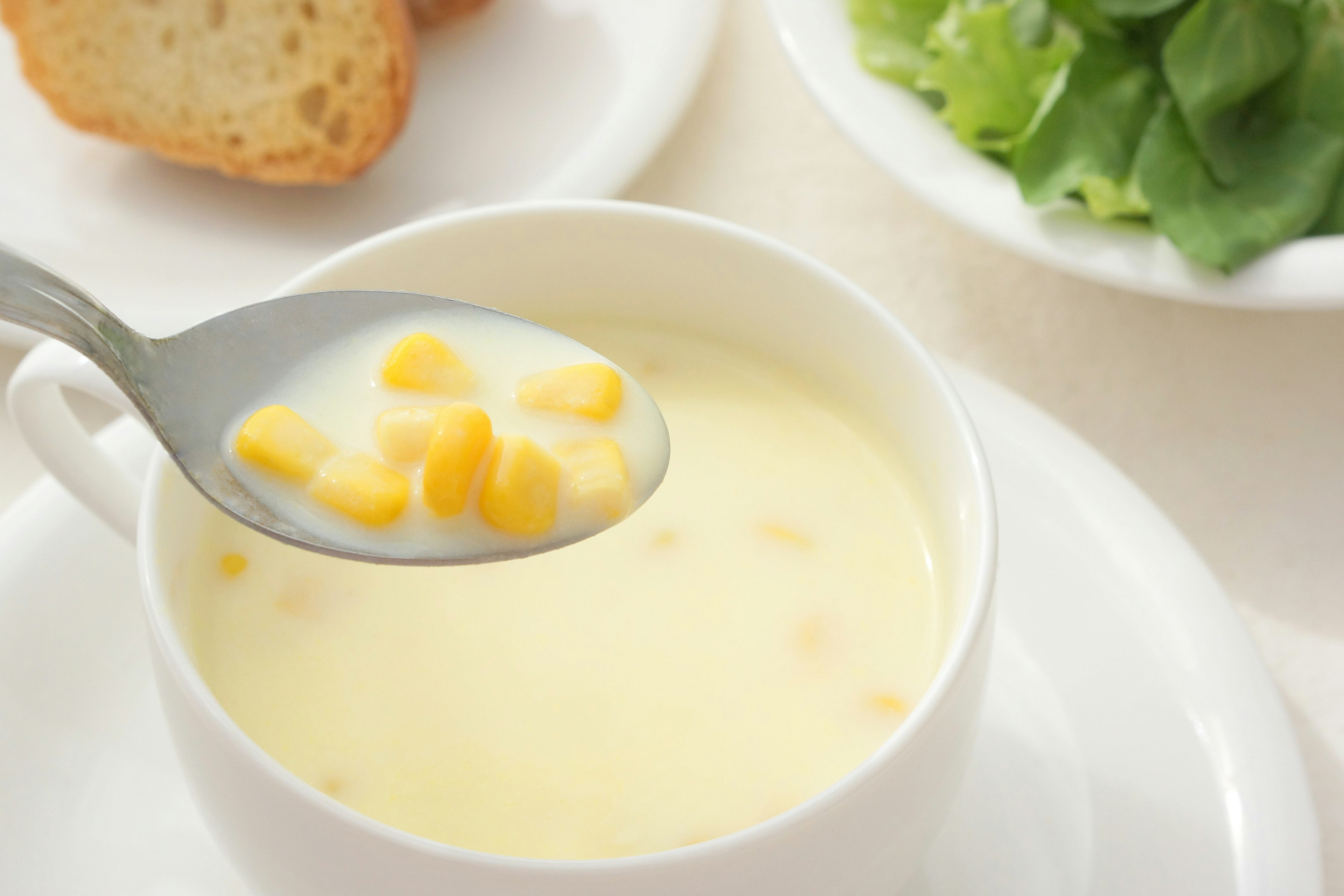 Sopa de maíz cremosa con pan y ensalada al lado