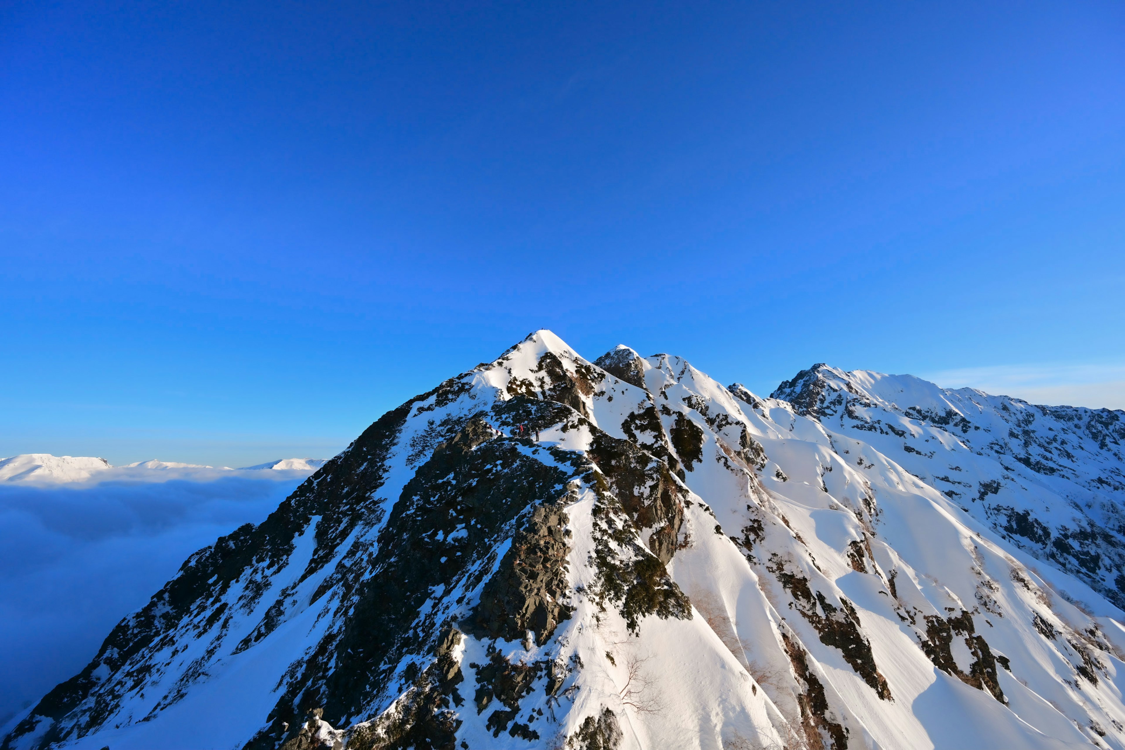 Schneebedeckter Berggipfel unter klarem blauen Himmel