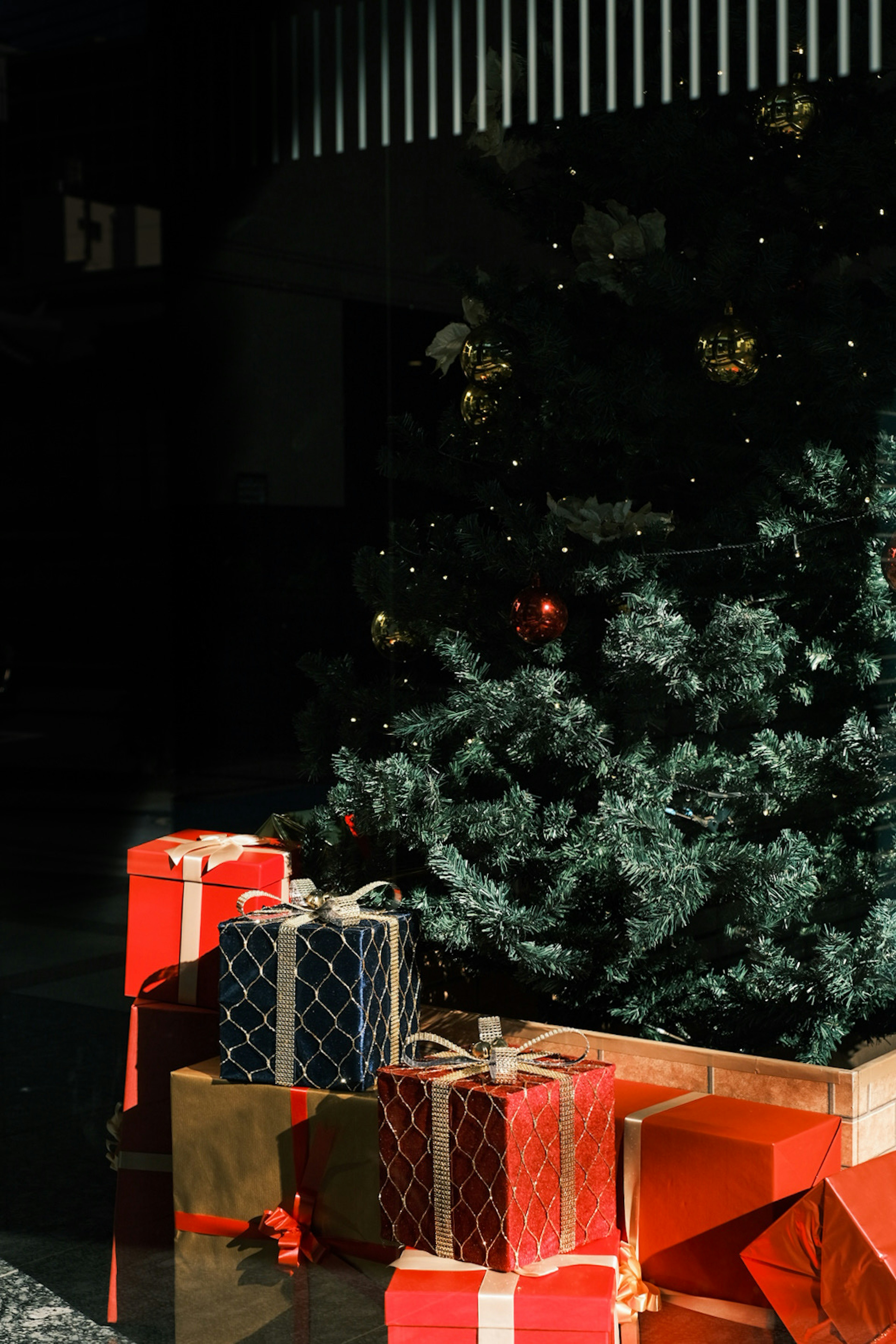 Presents in red and gold placed next to a Christmas tree