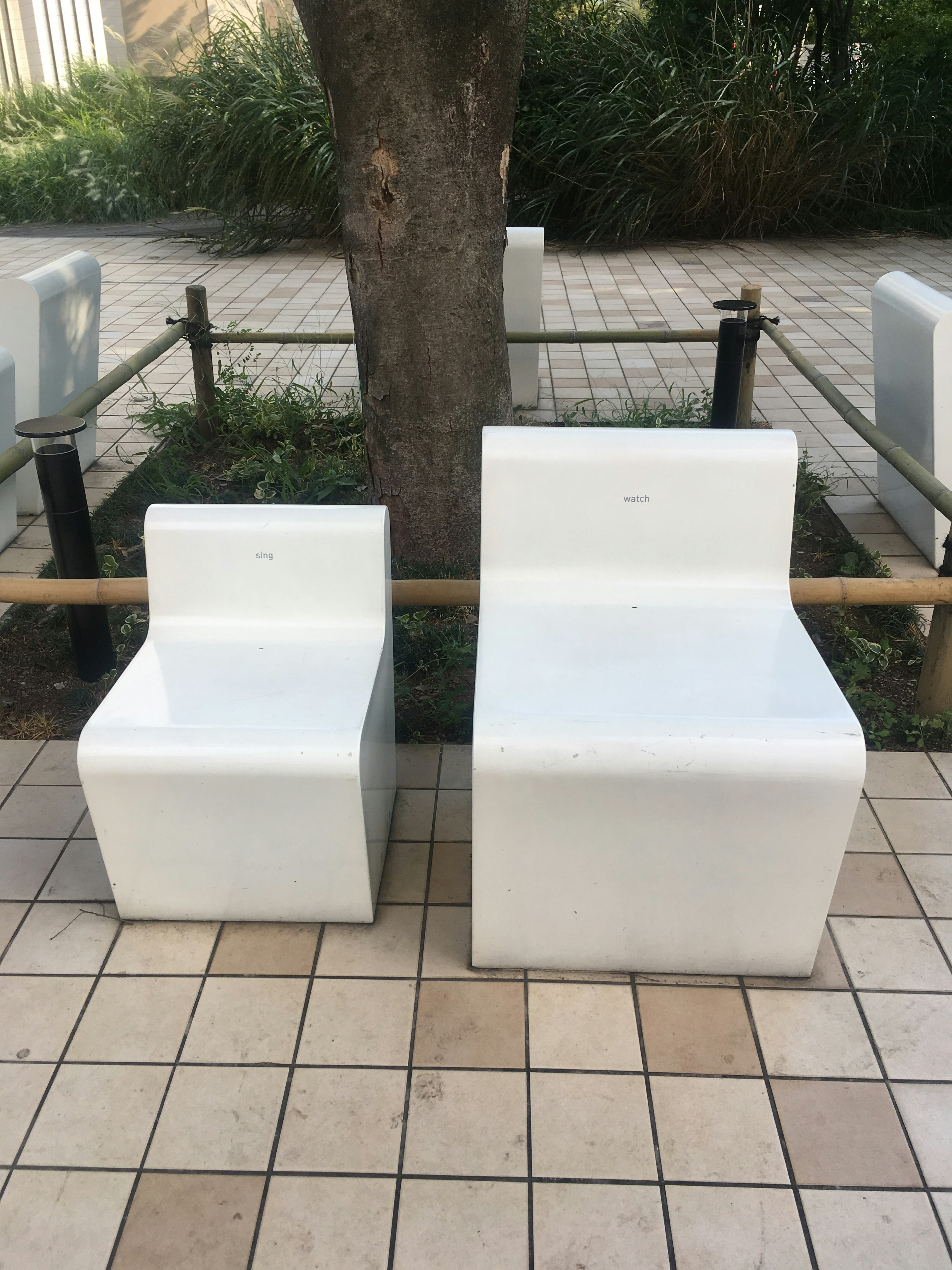 A park scene featuring two white chairs side by side one large and one small