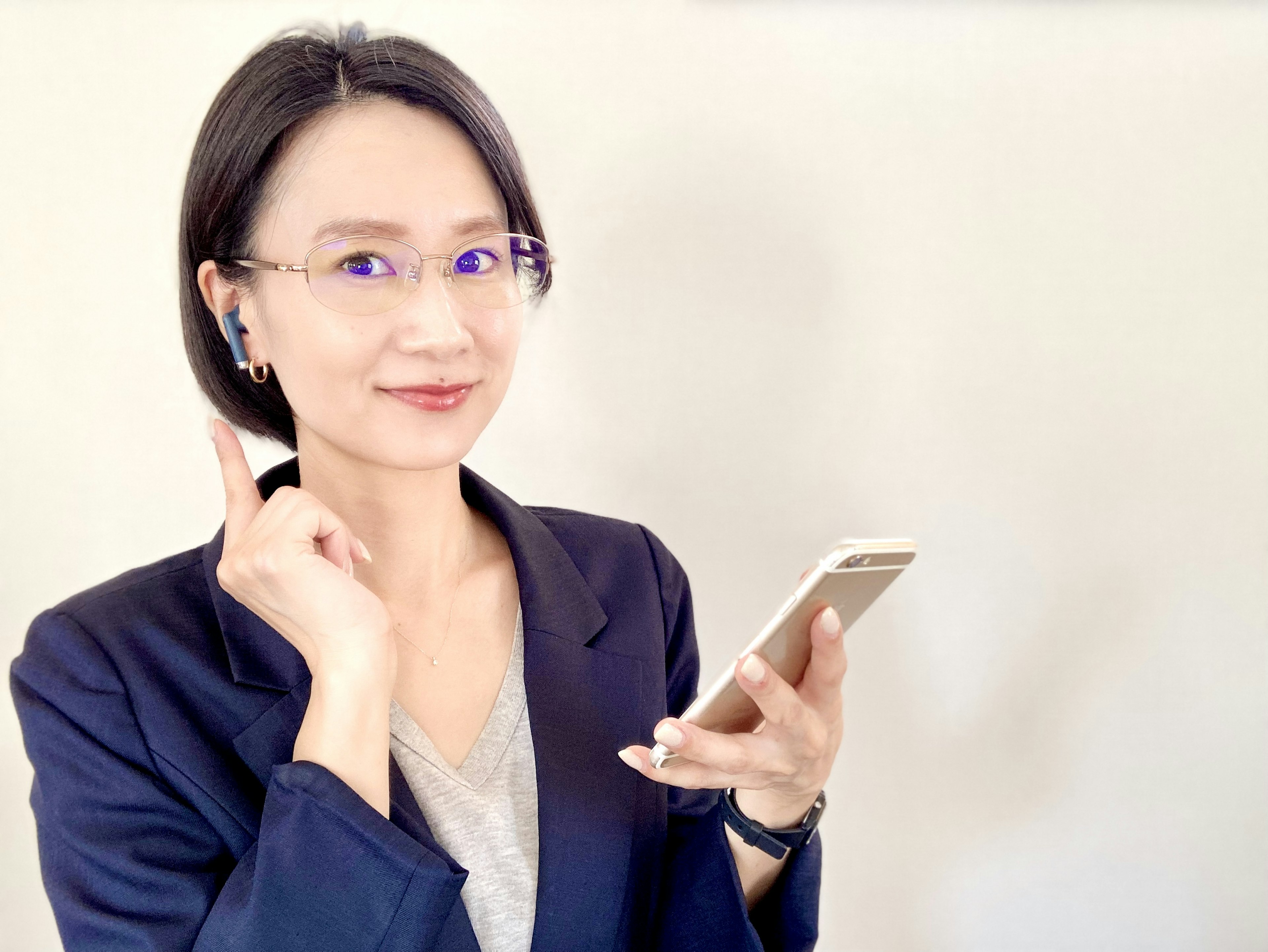 Potret wanita yang memegang smartphone dengan earphone di telinga