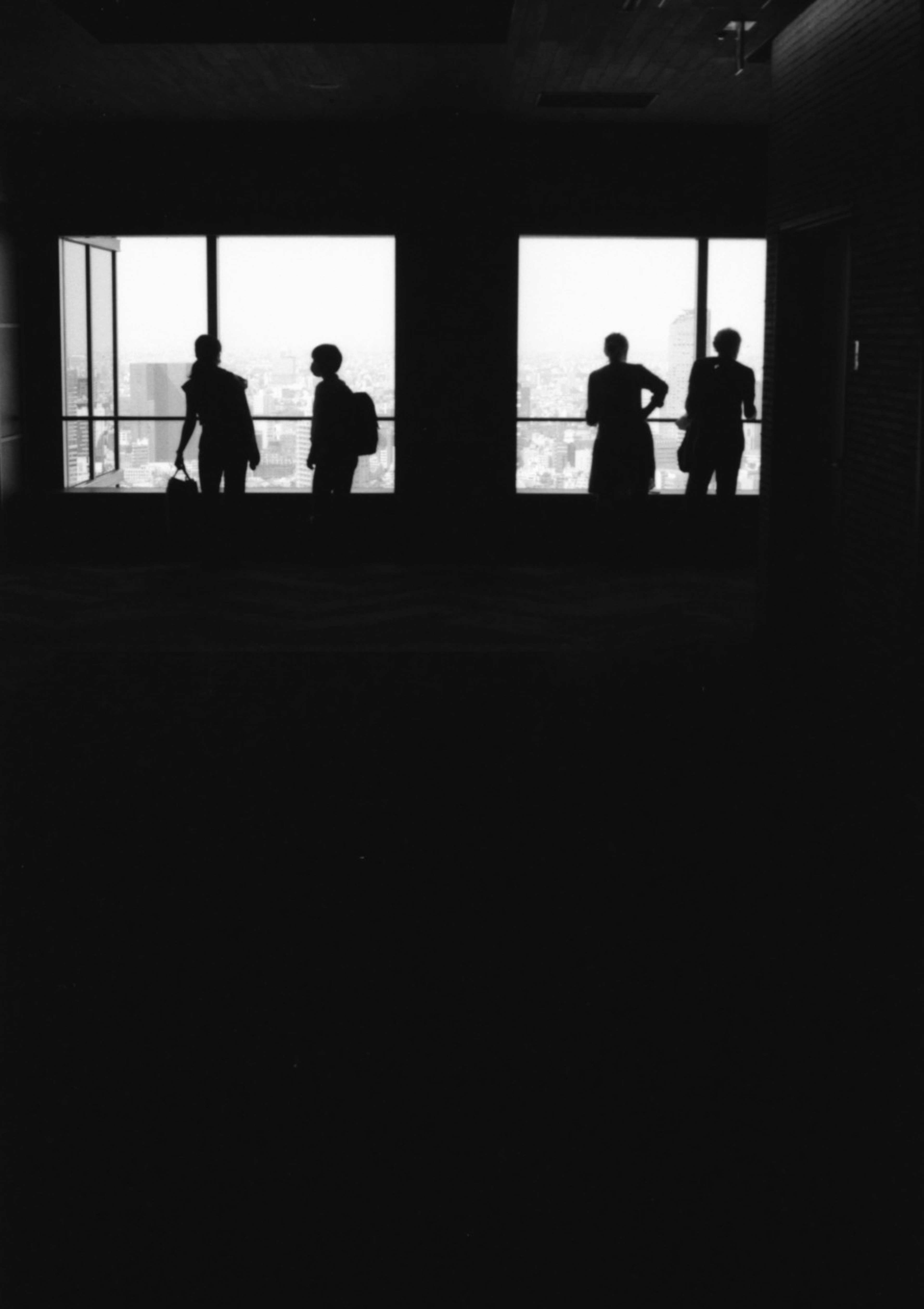 Silhouettes de personnes debout devant des fenêtres dans une photo en noir et blanc