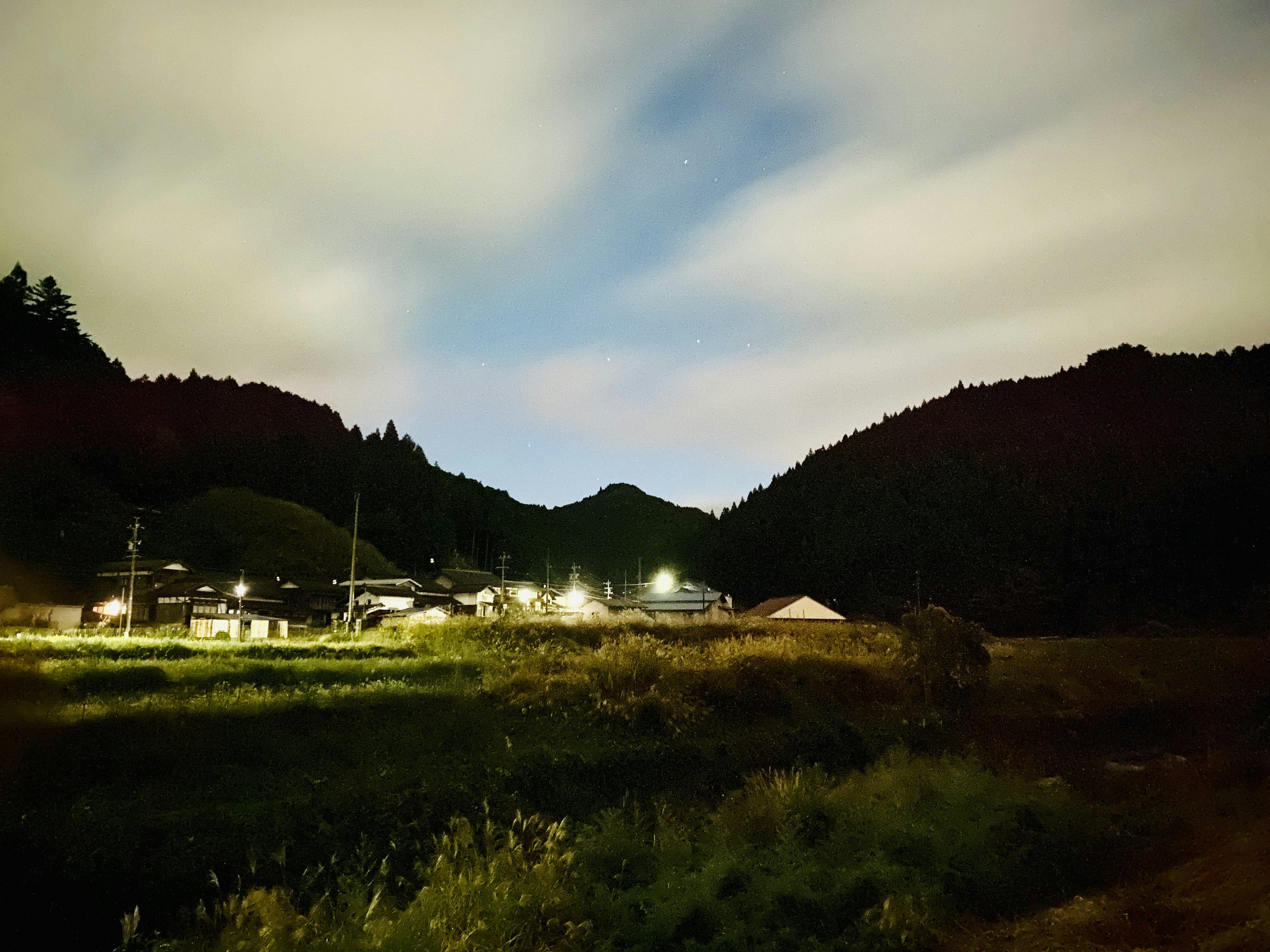 Scène nocturne rurale tranquille avec des collines et un village