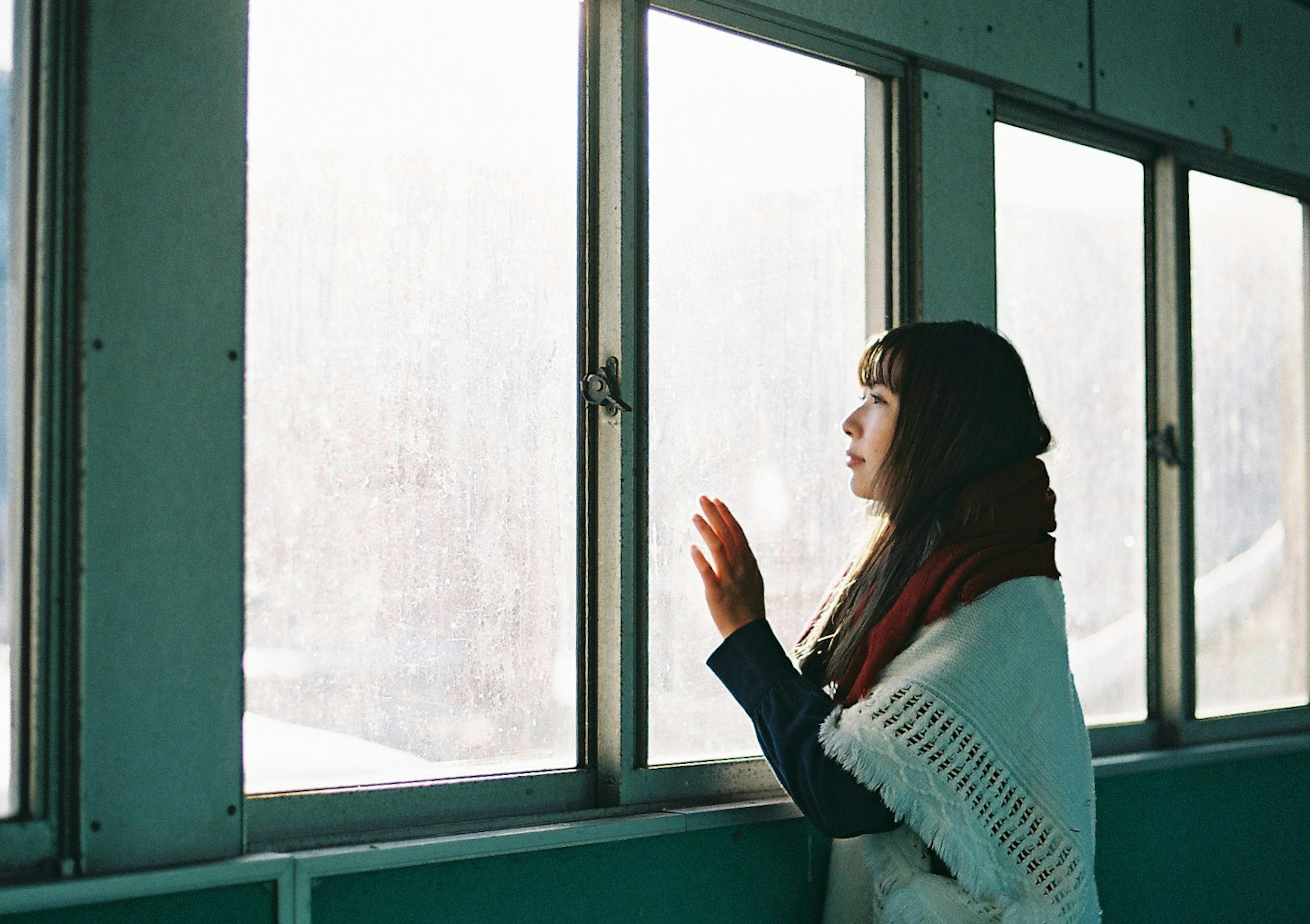 Frau mit weißem Schal, die aus dem Fenster schaut