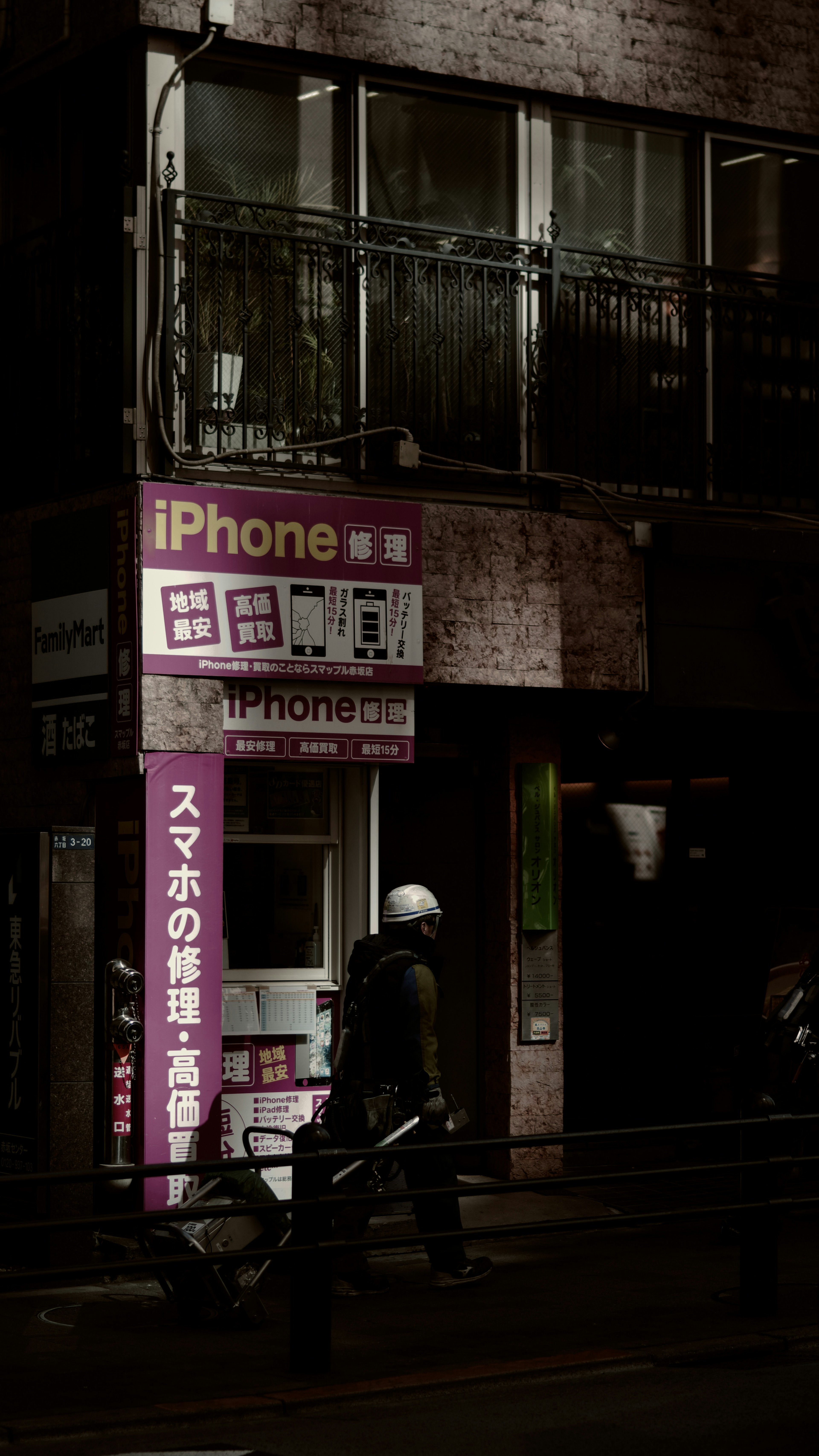 iPhone repair shop sign on a dark street with a person working