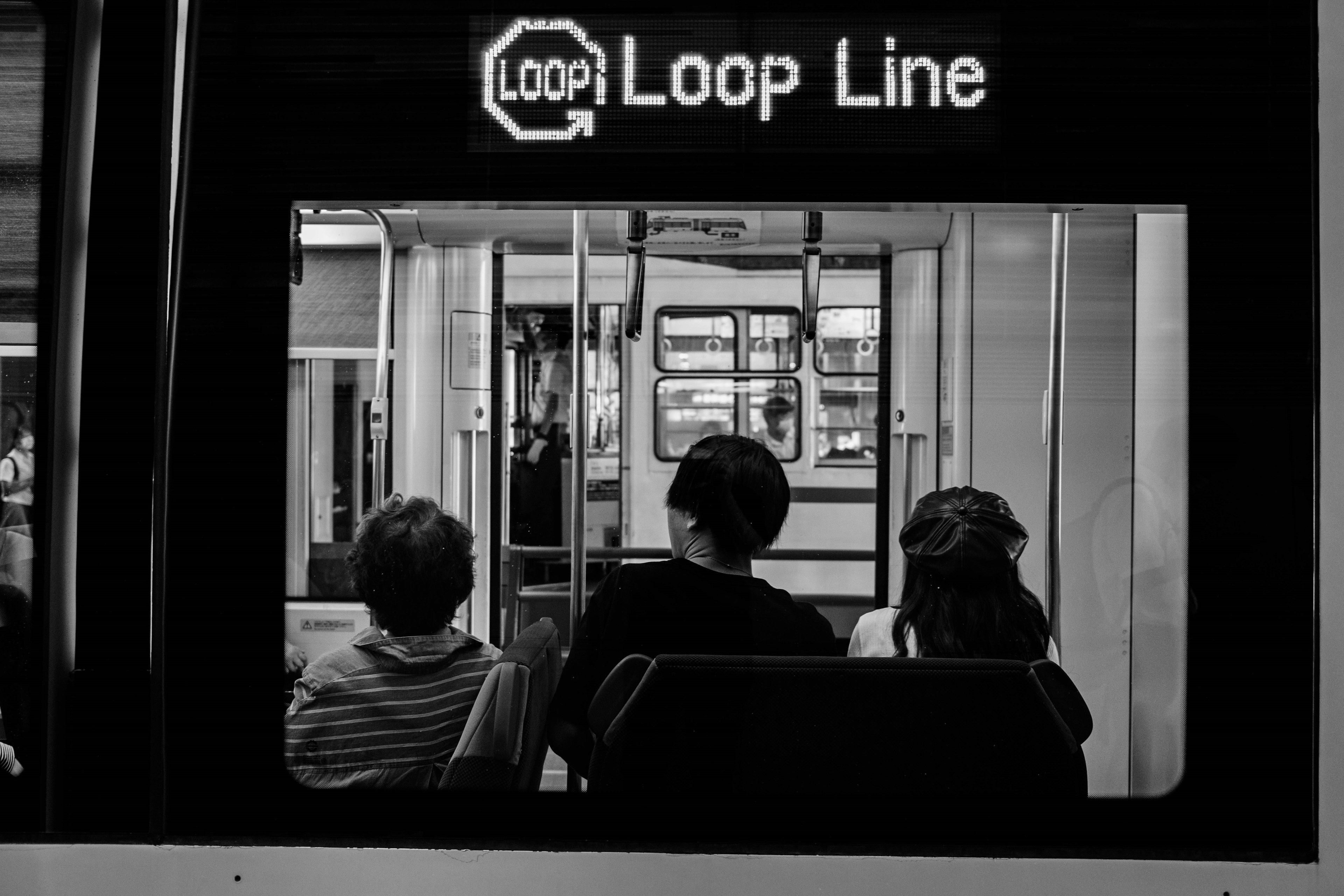 คนที่นั่งอยู่ในรถไฟที่มีป้าย Loop Line ข้างบน