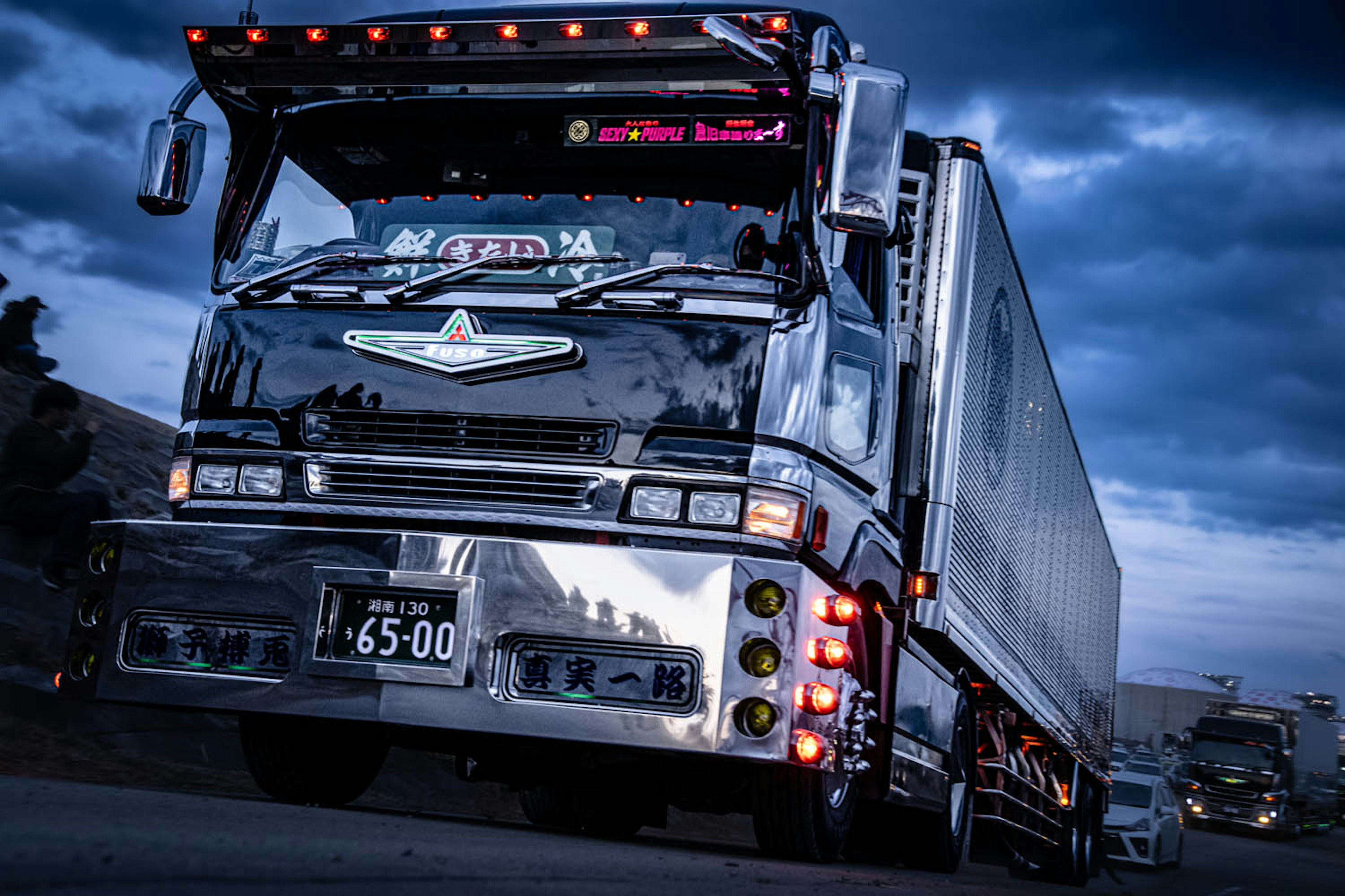 A black truck driving on the road at night