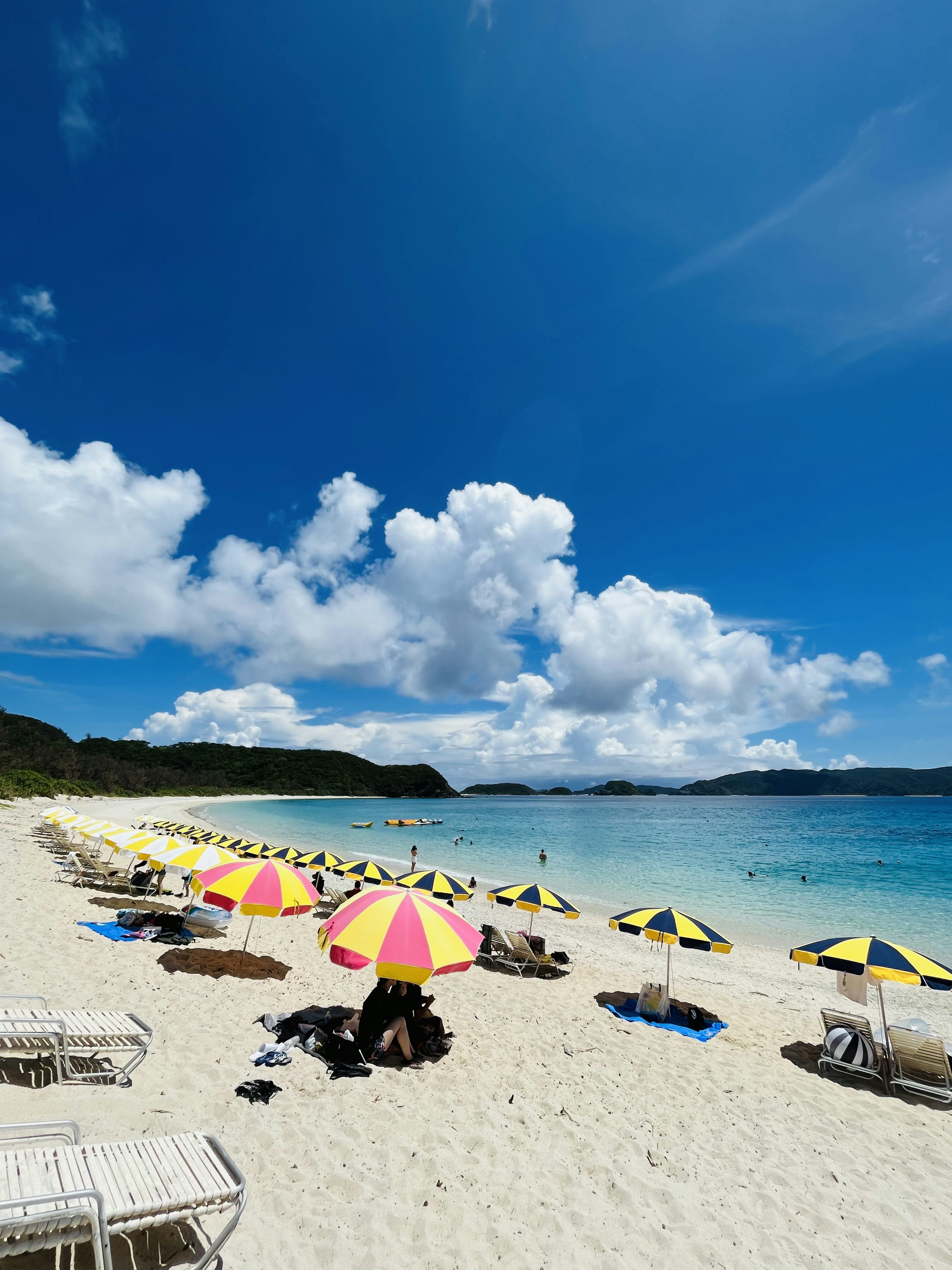 Plage magnifique avec des parasols colorés sous un ciel bleu et des nuages blancs