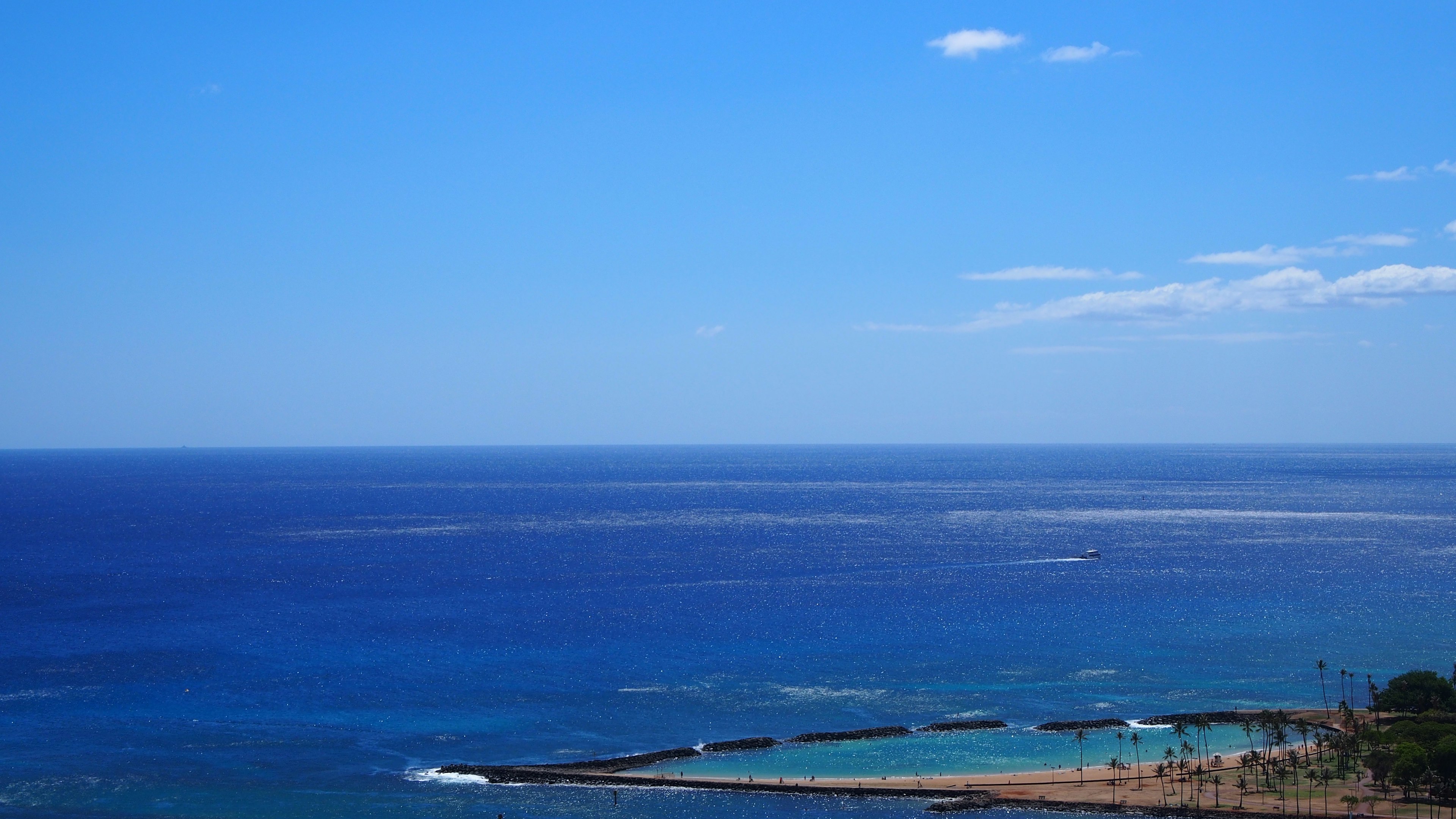 Amplia vista del océano bajo un cielo azul claro con tonos de azul y suaves olas