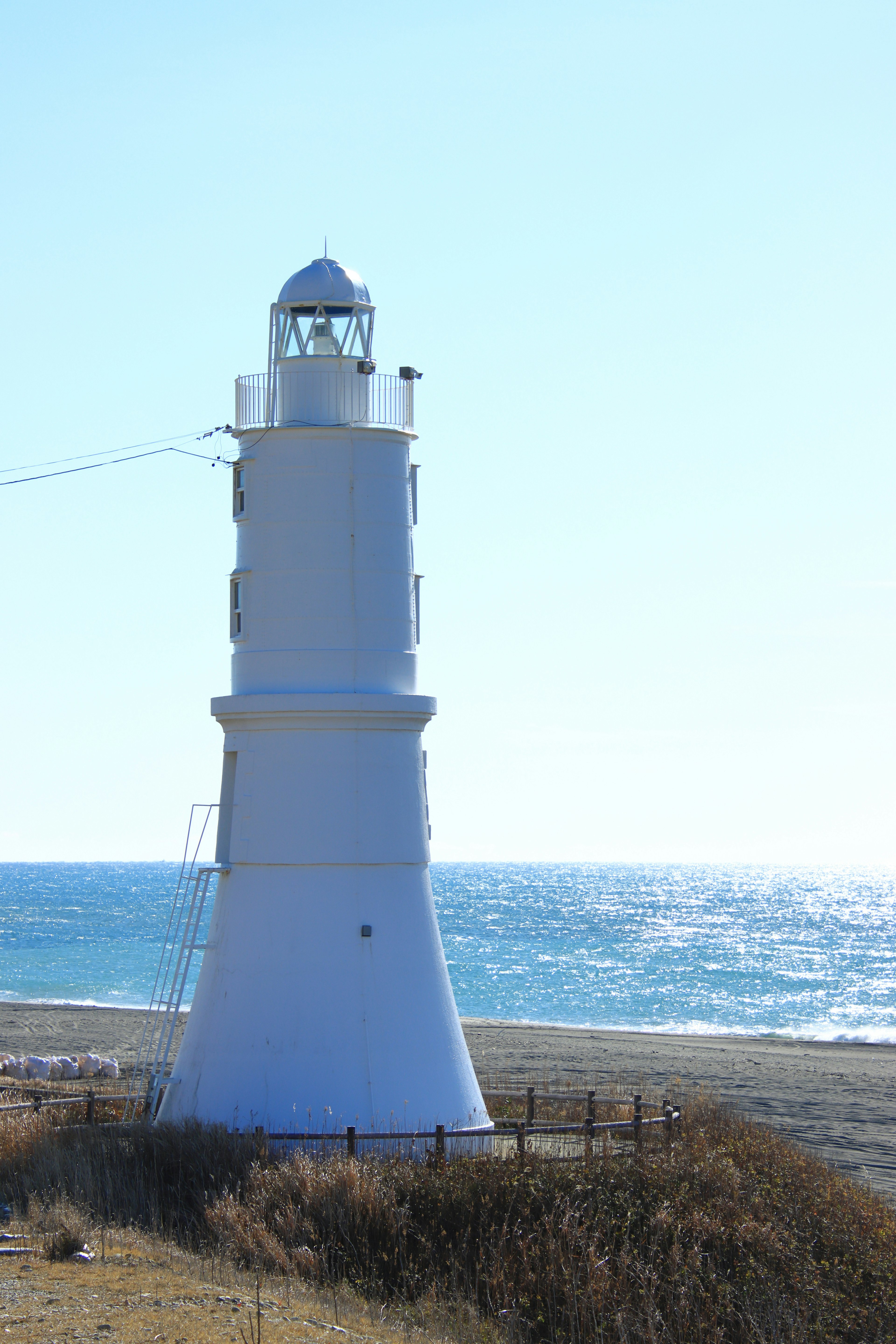 Un faro bianco che si erge sulla costa sotto un cielo blu