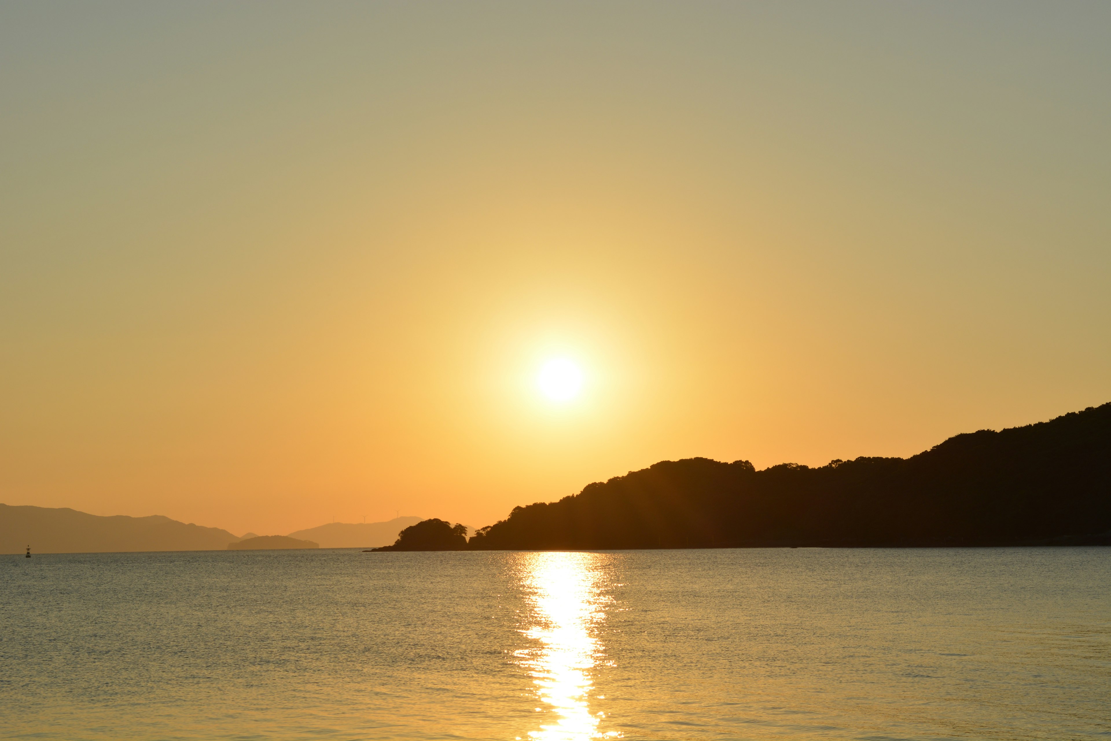 Hermoso atardecer sobre el mar con colinas en silueta