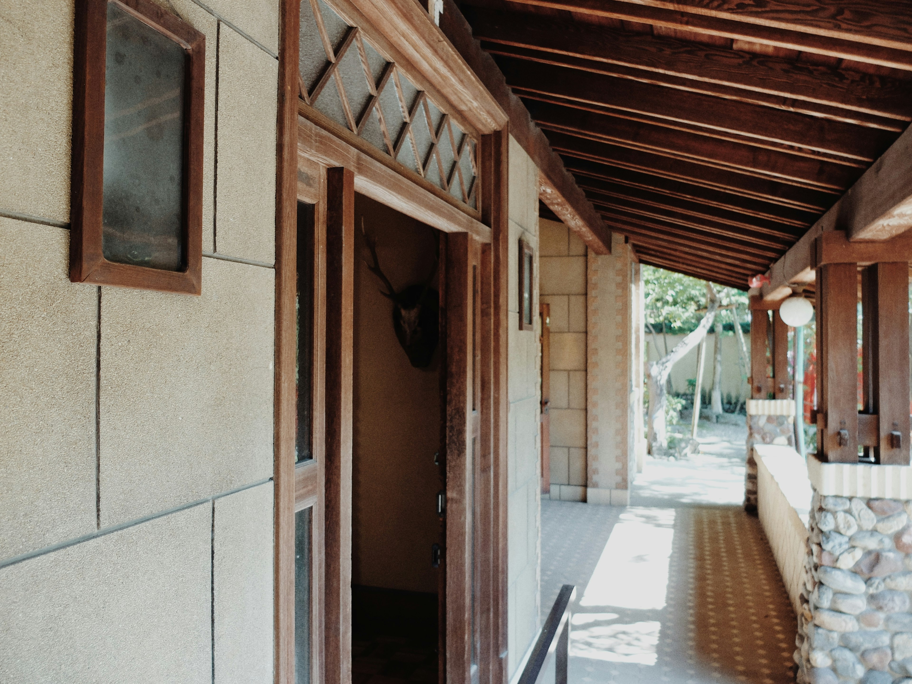 Tampilan pintu masuk dengan pintu kayu dan dinding batu