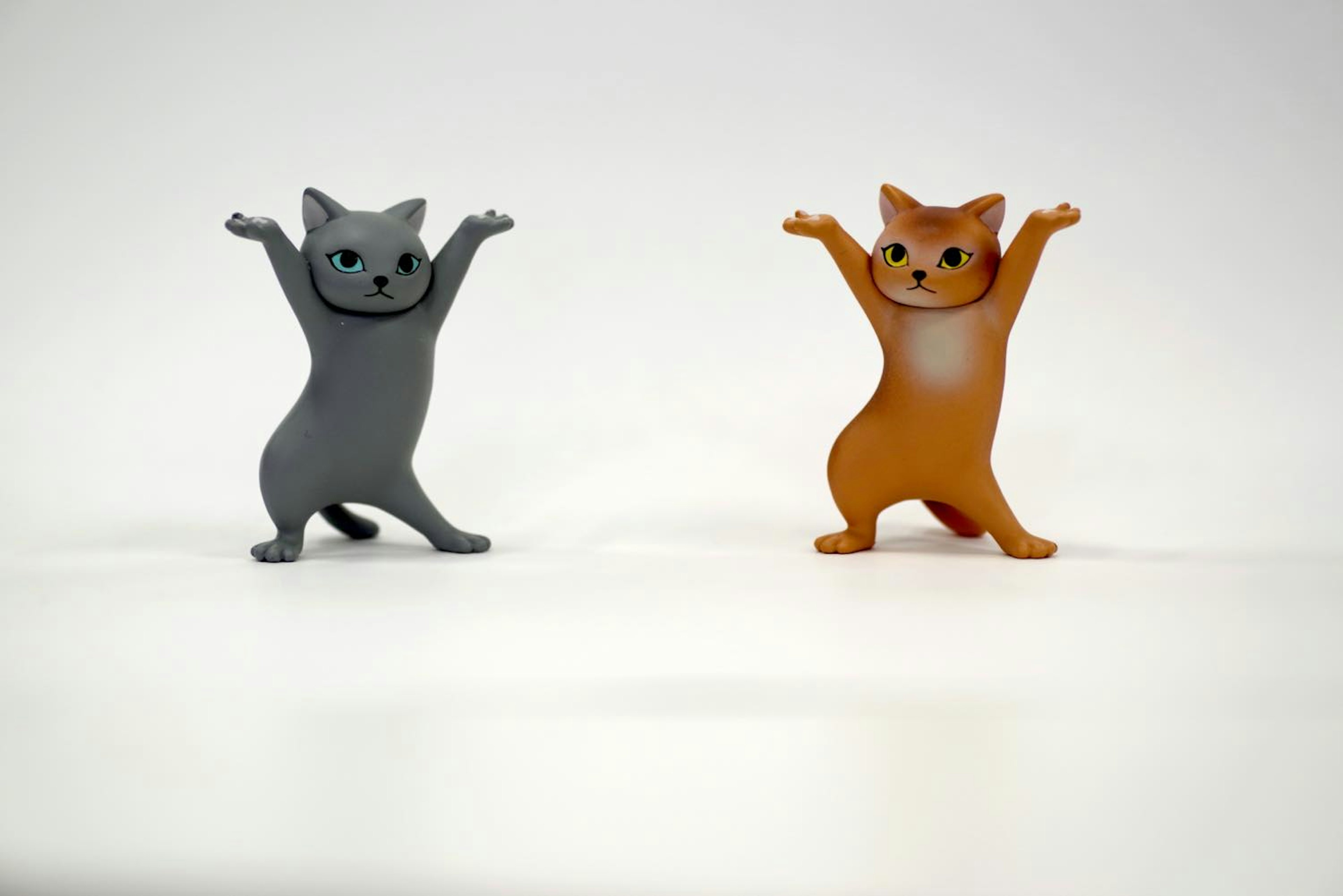 Figuras de gatos gris y naranja de pie felices