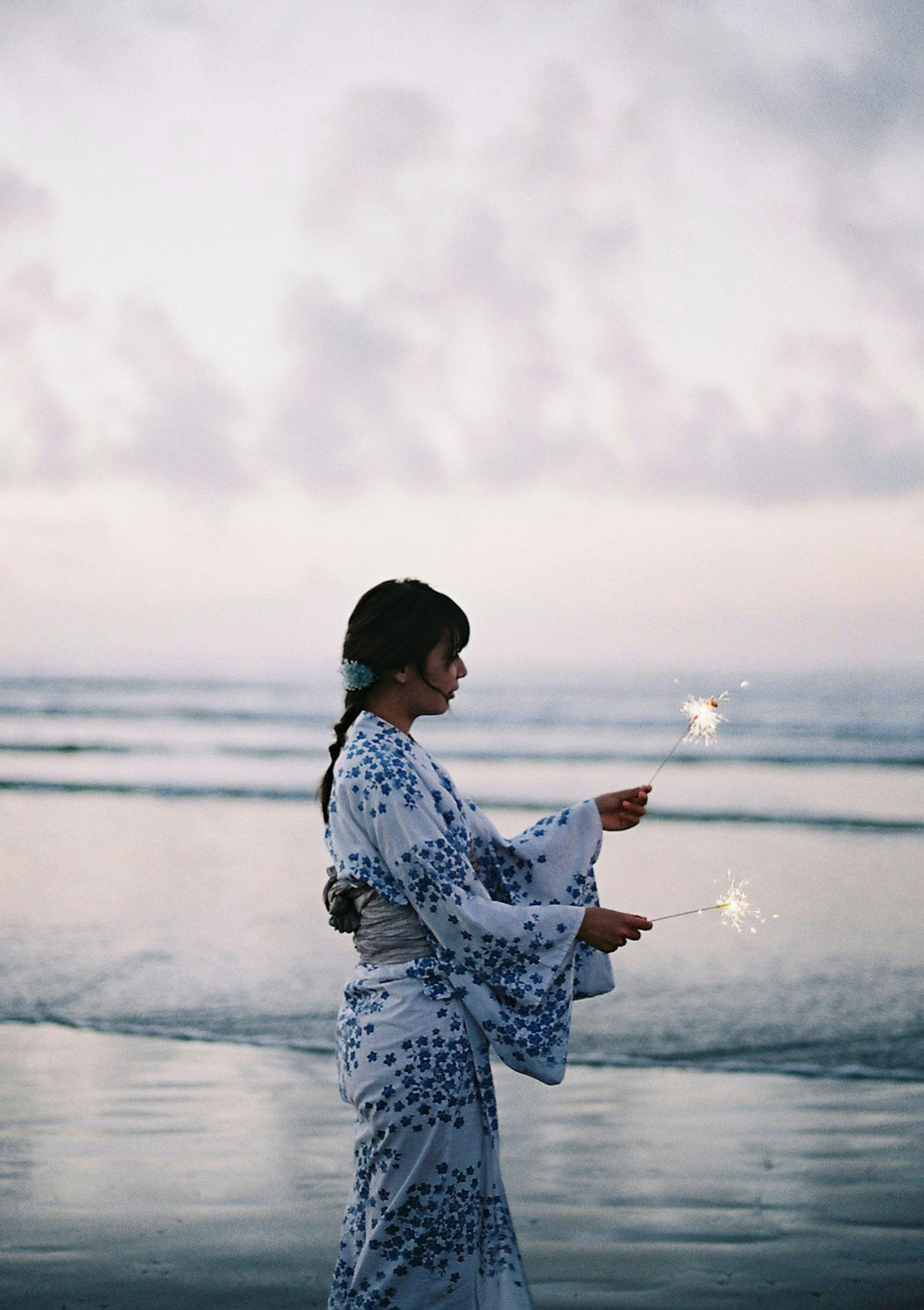 海辺で浴衣を着た女性が夕暮れ時に立っている