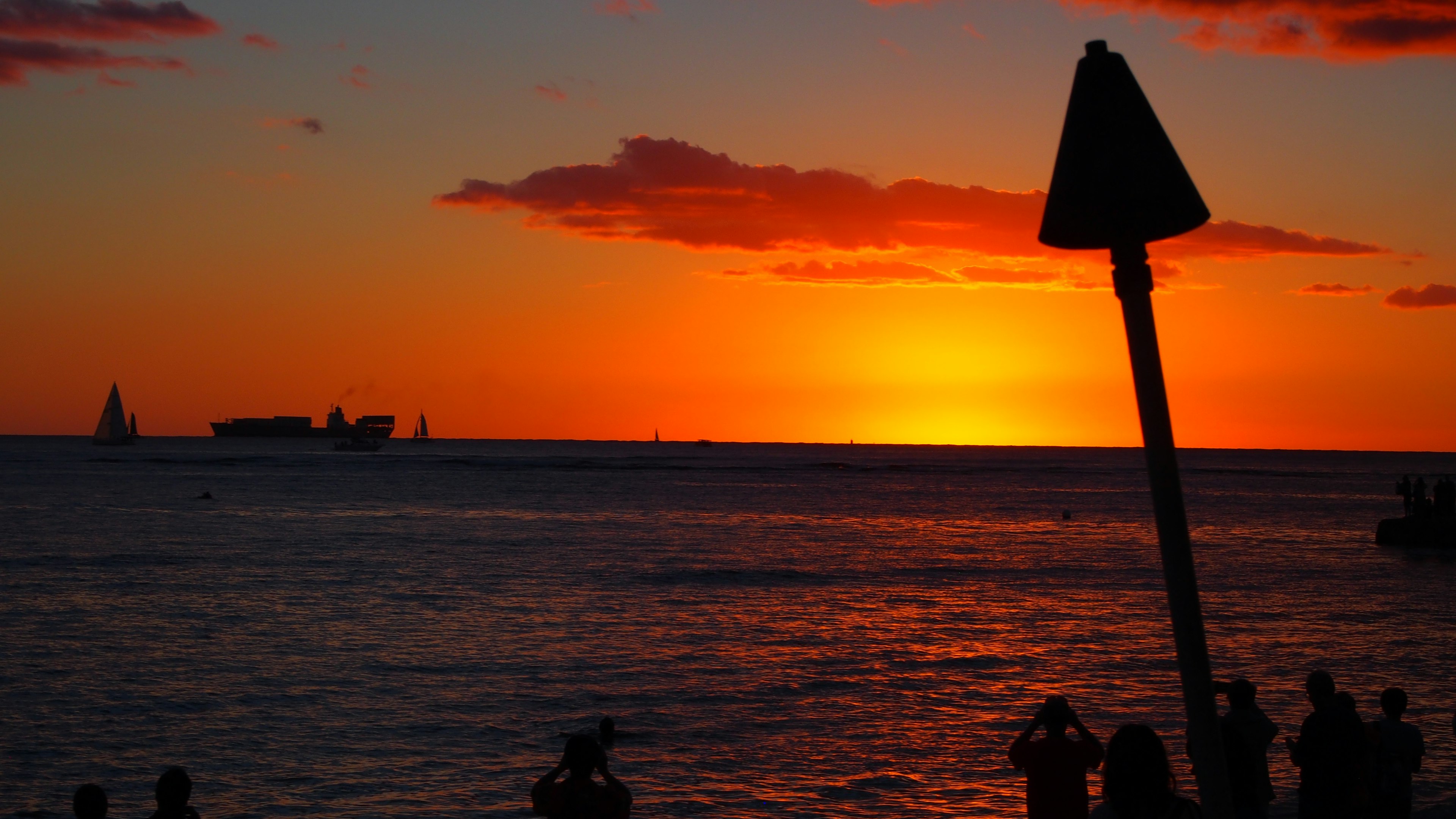 Silhouette von Menschen, die den Sonnenuntergang über dem Ozean beobachten