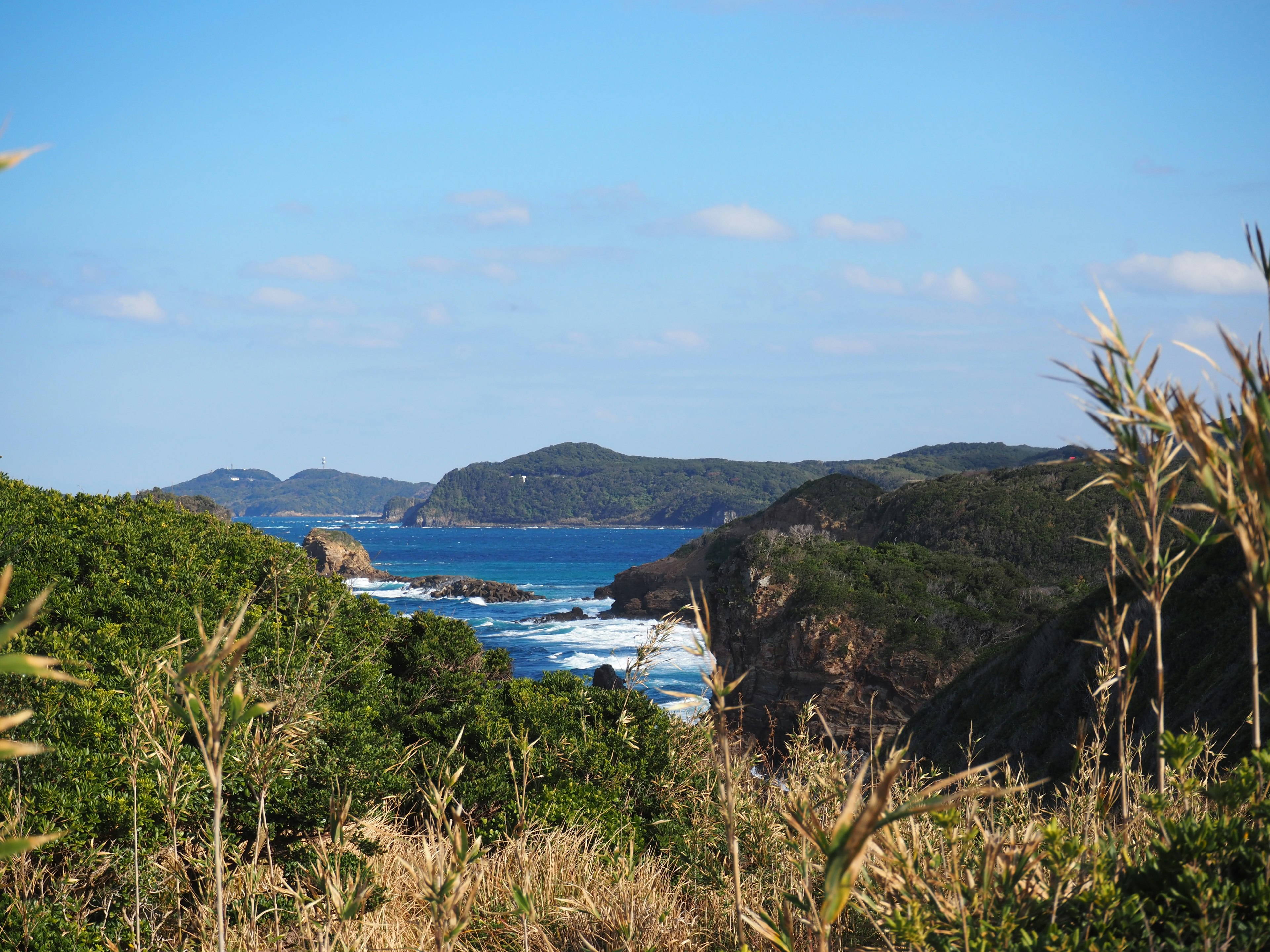 Scenic view of green hills and blue ocean under a clear sky