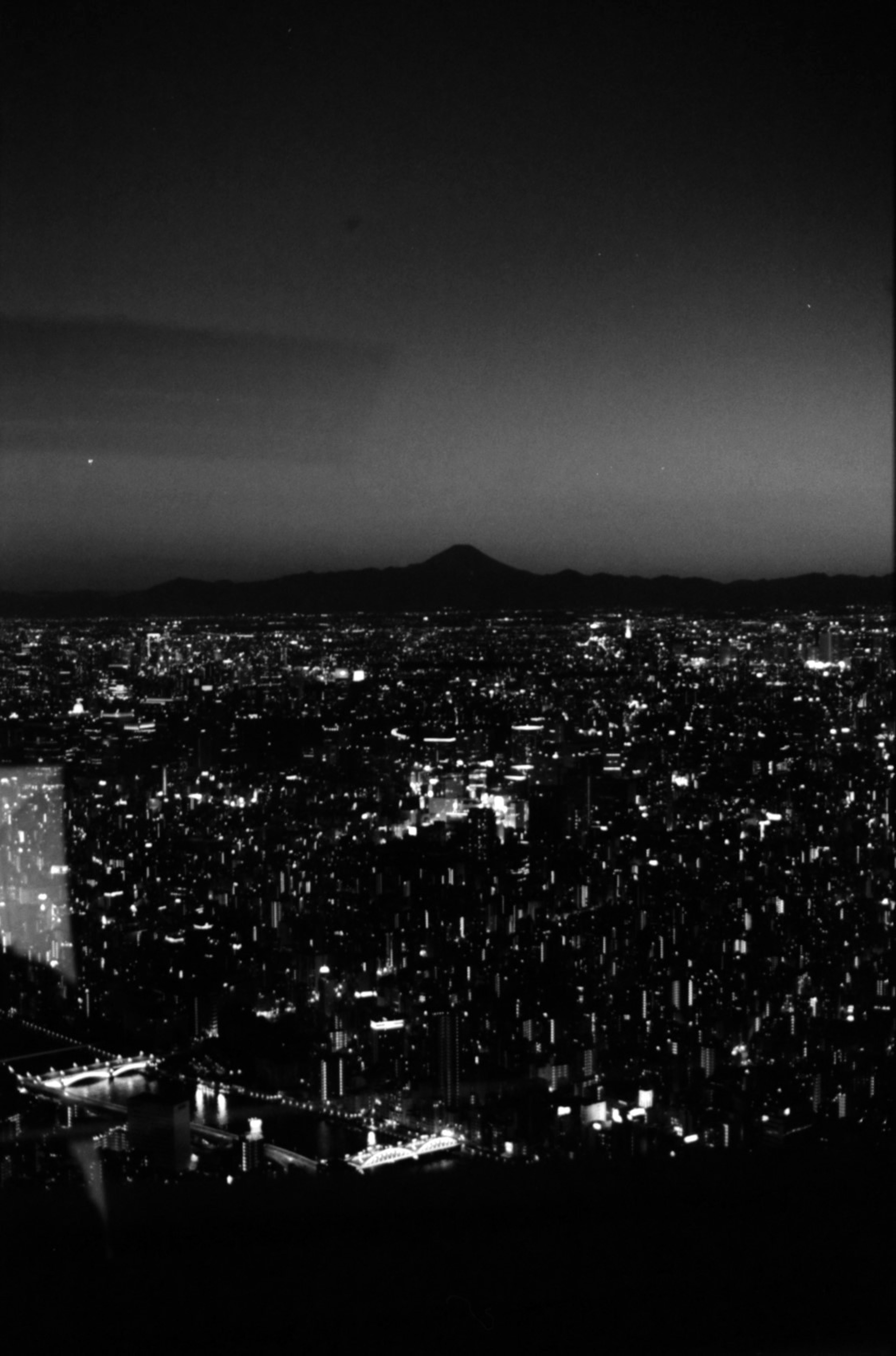 東京の夜景と富士山のシルエットが見えるモノクロ画像