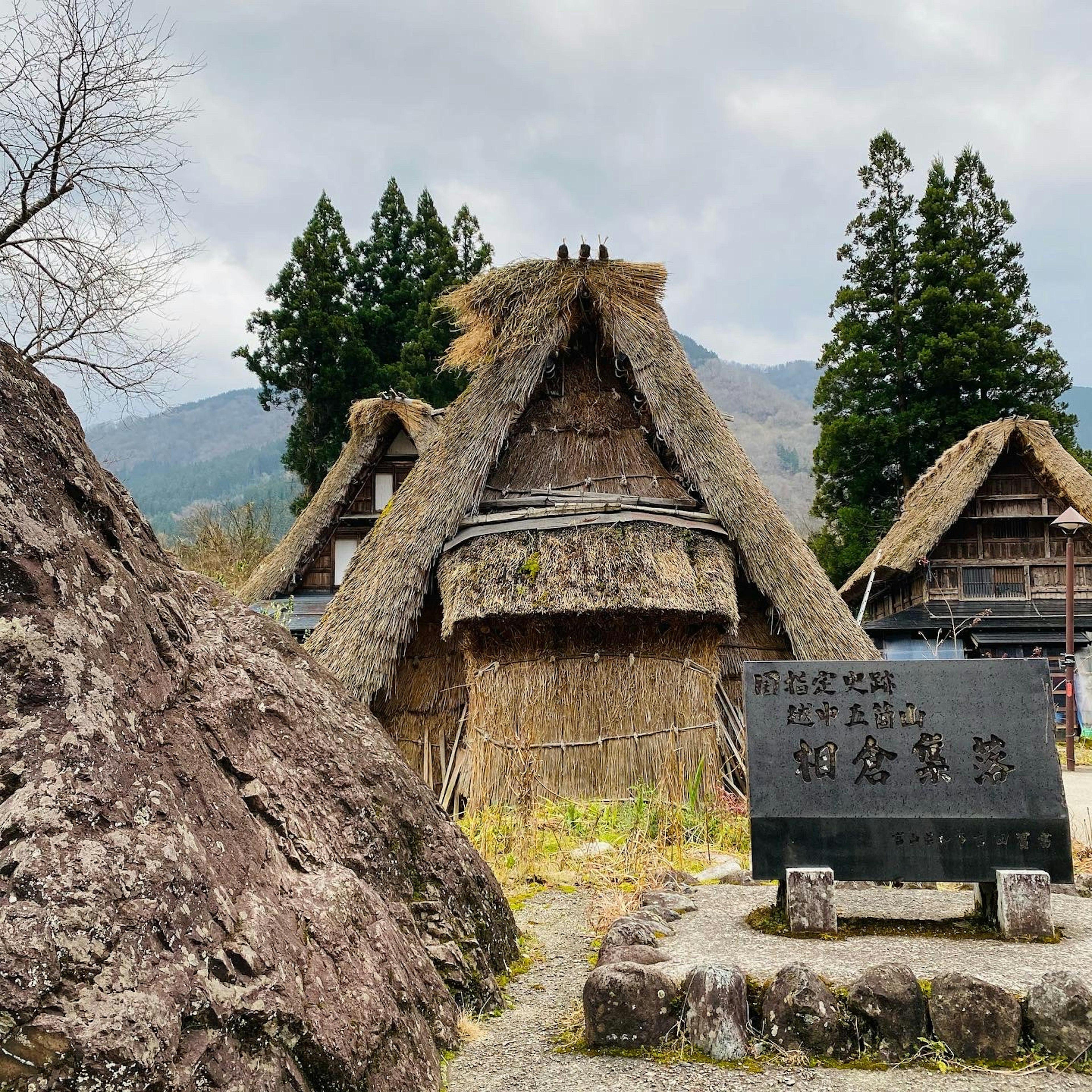 Traditional Japanese gassho-zukuri house with a stone monument