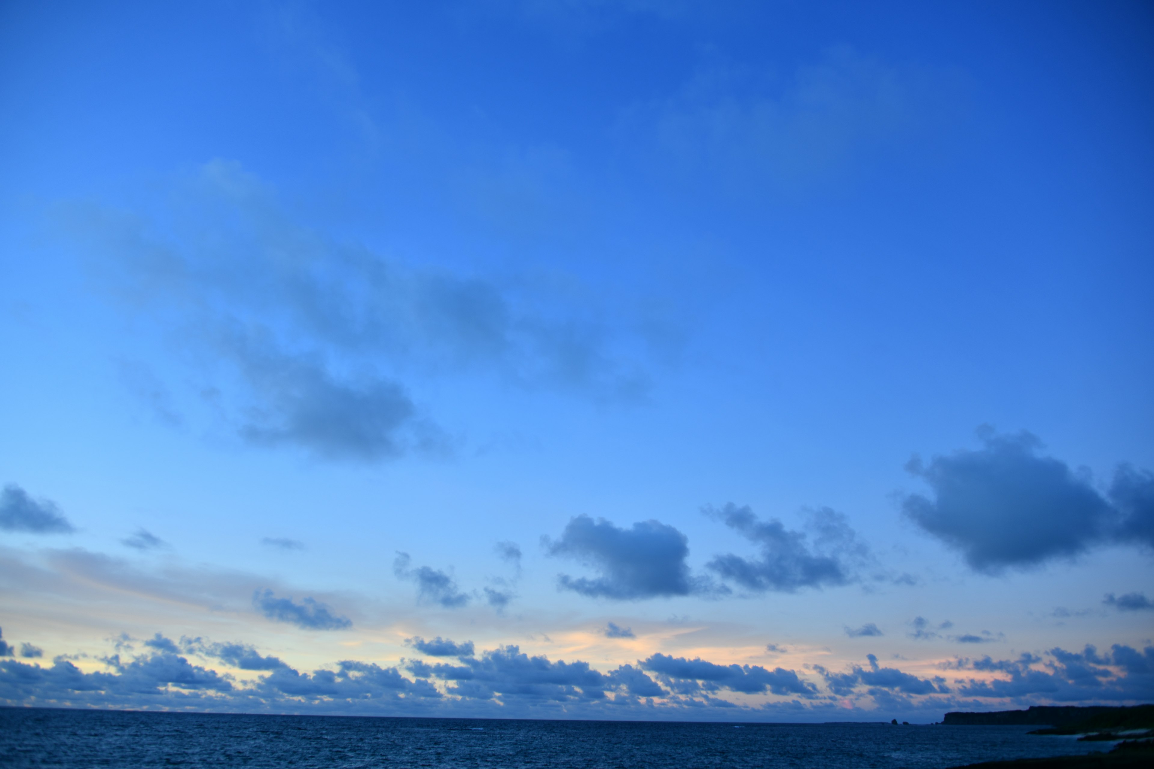 Vast blue sky with scattered clouds above the ocean