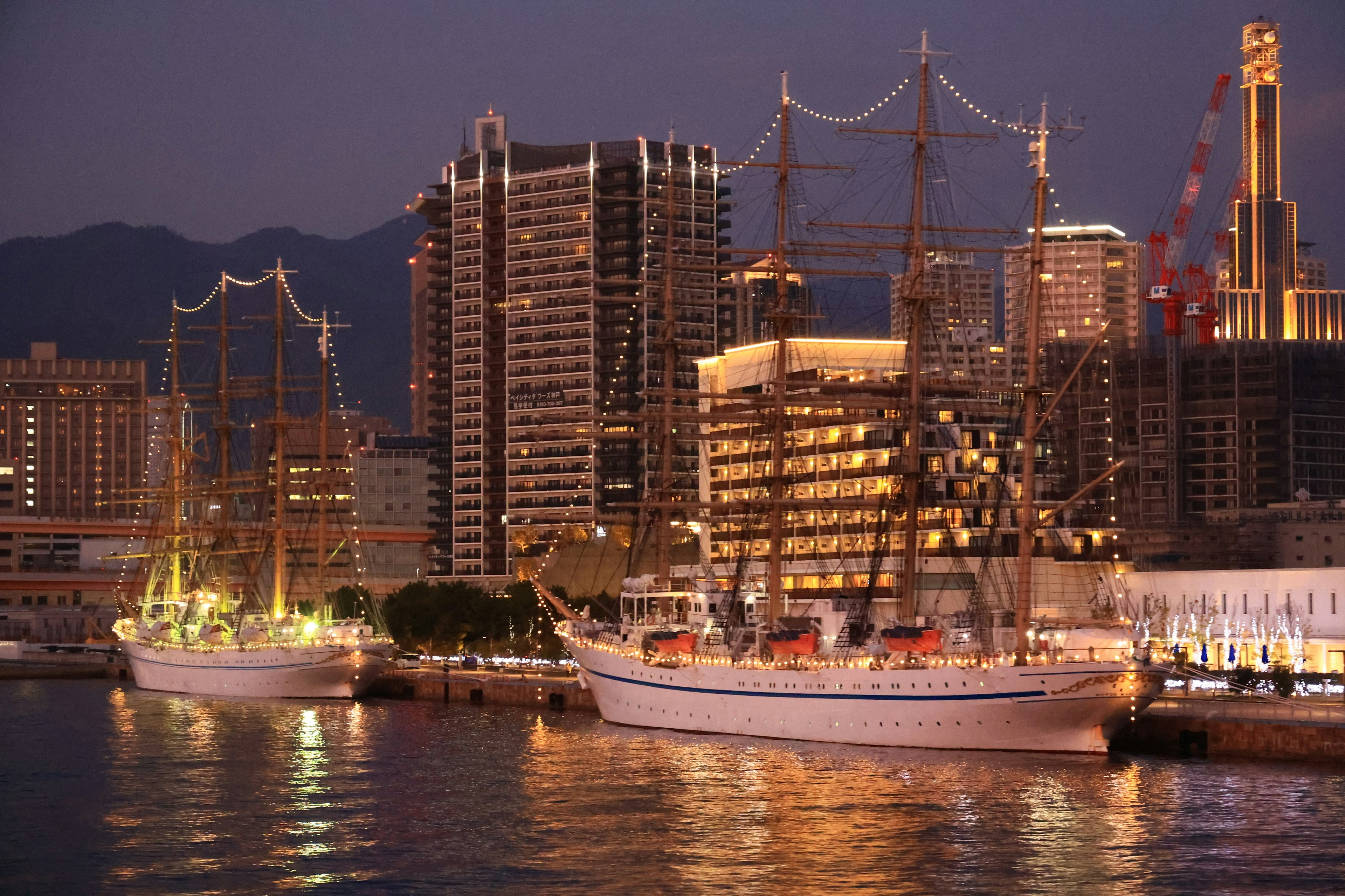 Bella vista di navi a vela lussuose e grattacieli di notte vicino al mare