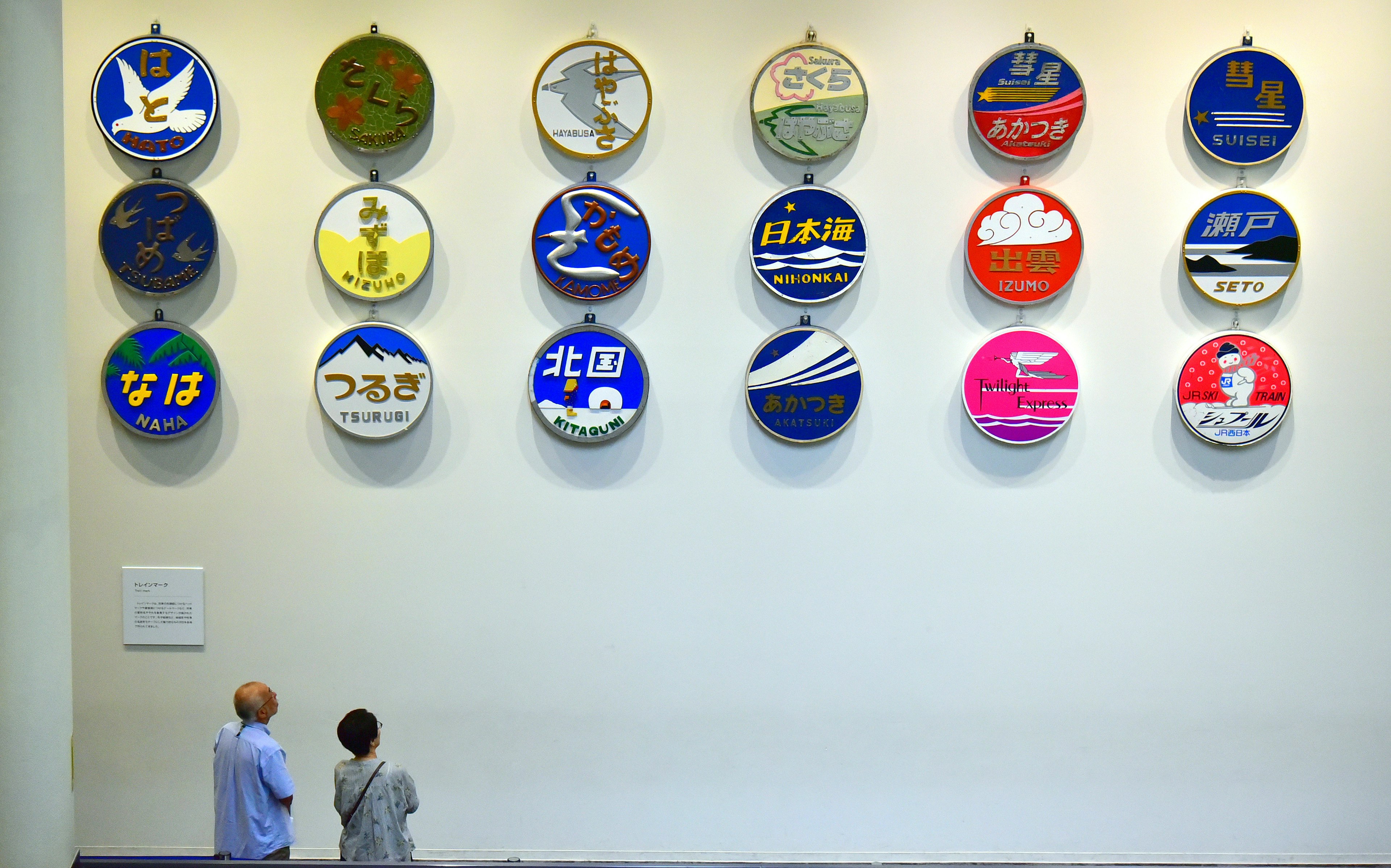 Colorful circular signs hanging on a wall with two people looking up at them