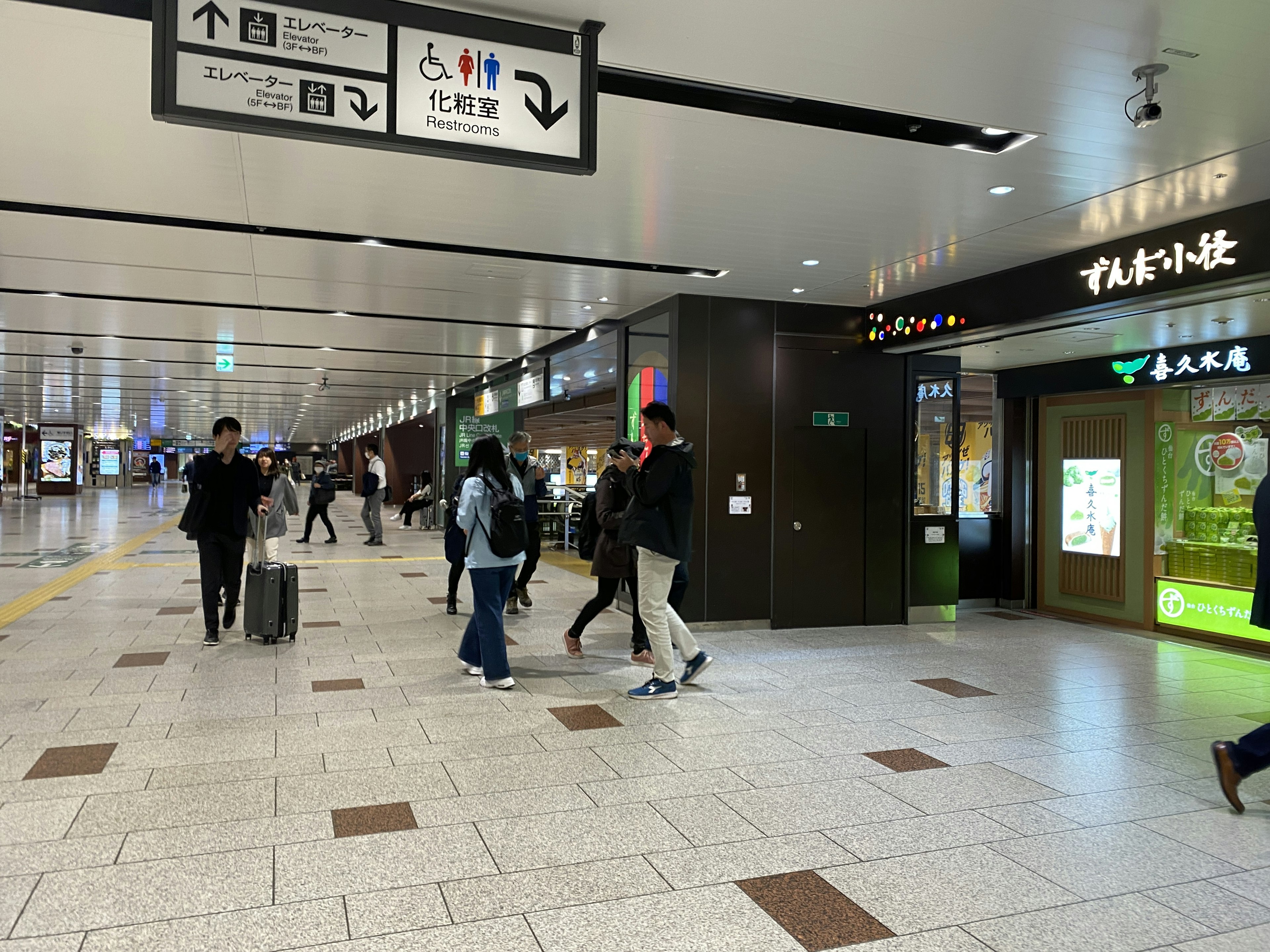 Interior of a busy train station with shops and travelers